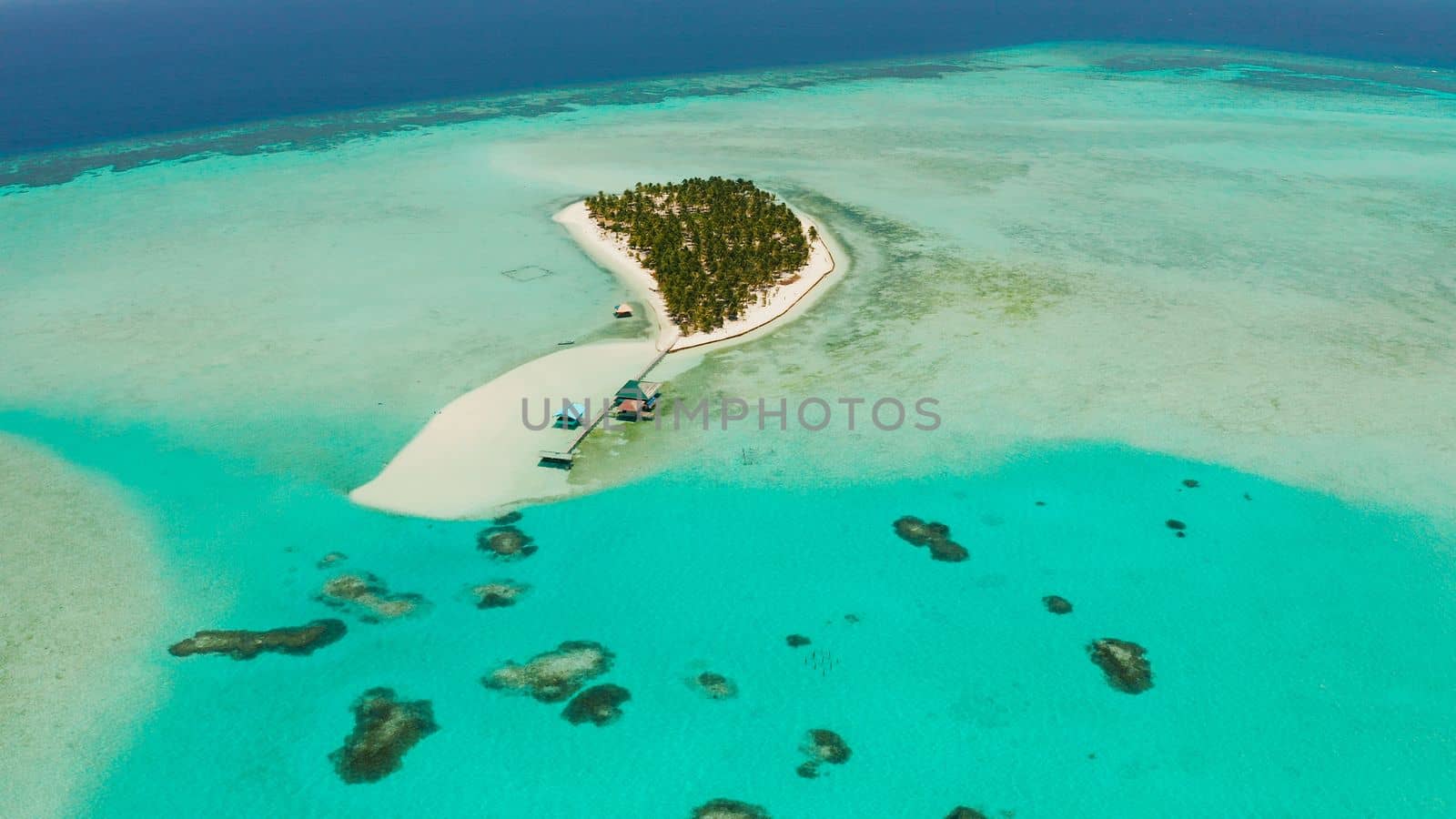 Seascape with beautiful beach and tropical island surrounded by a coral reef from above. Onok Island, Balabac, Philippines. Summer and travel vacation concept