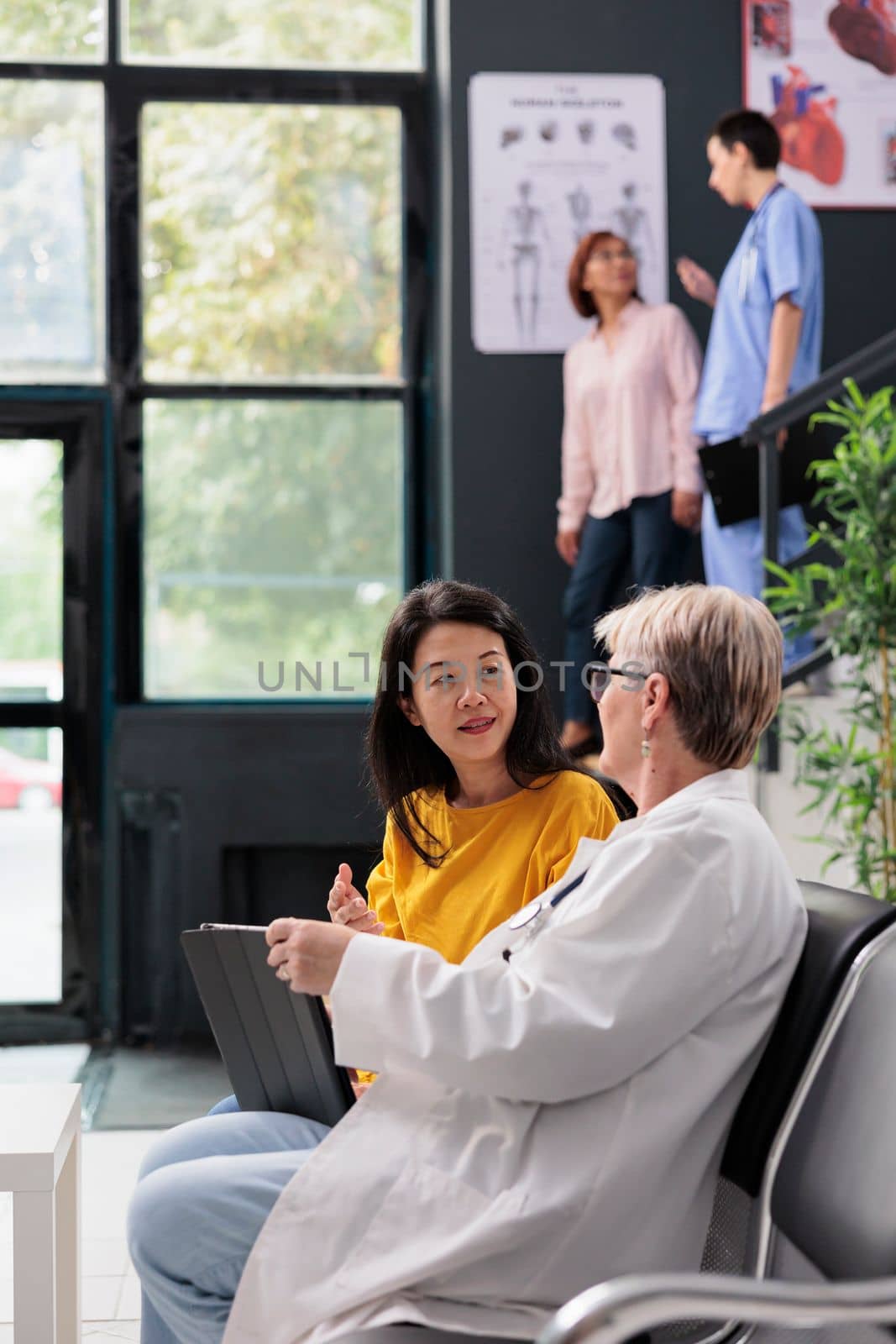 Old physician and patient doing checkup visit in hospital by DCStudio