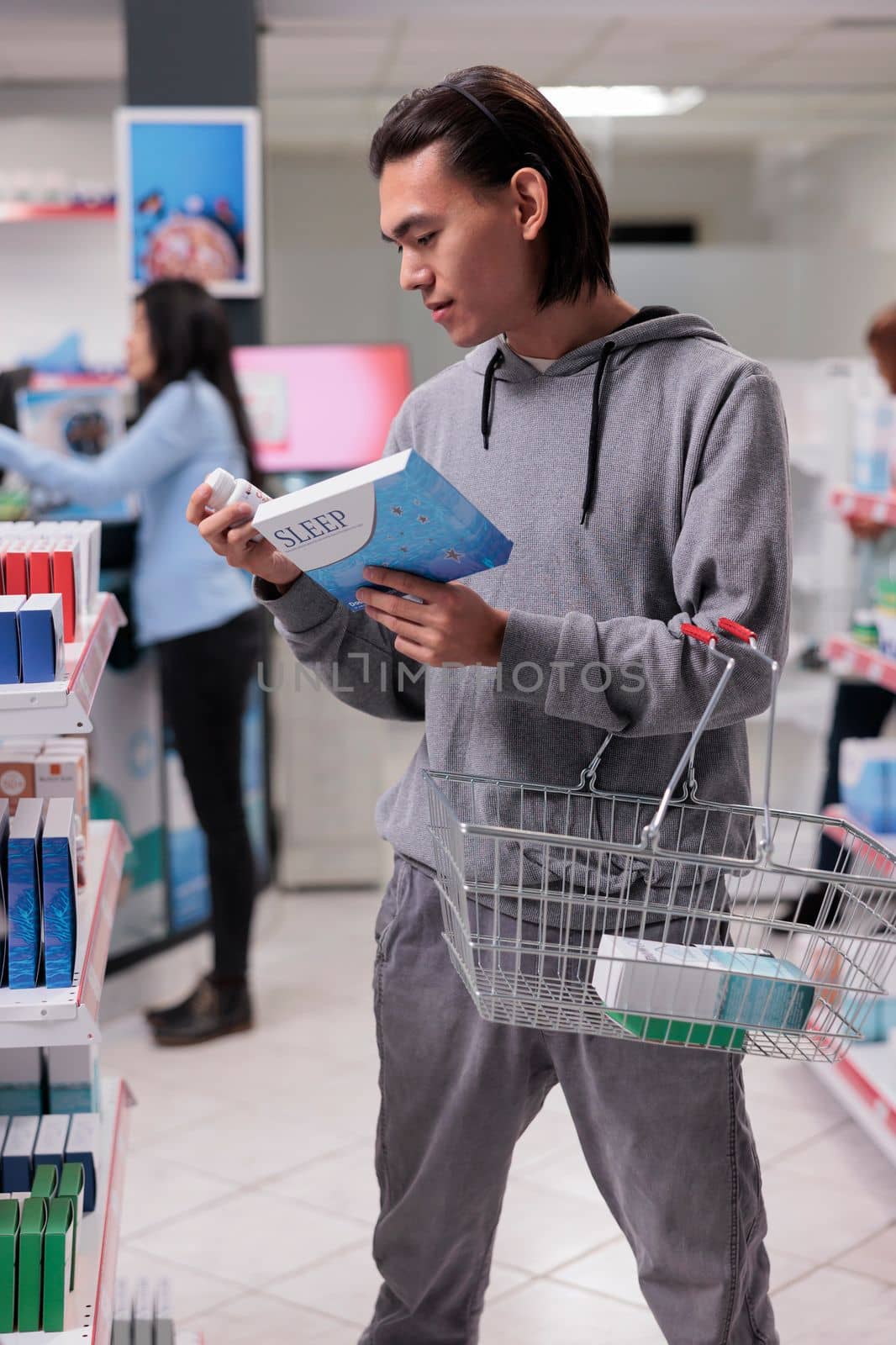 Young man looking at box of sleeping pills in drugstore, buying pharmaceutical sedatives to help with health care. Reading leaflet package of medical treatment, prescription medicine.