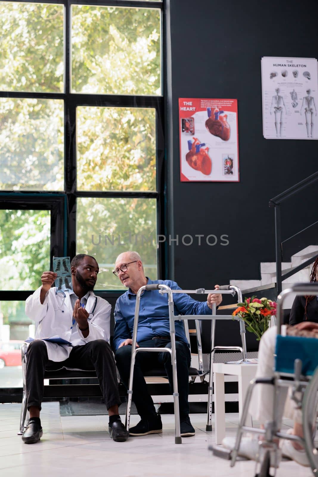 Practitioner medic looking at medical radiography with senior injured patient by DCStudio