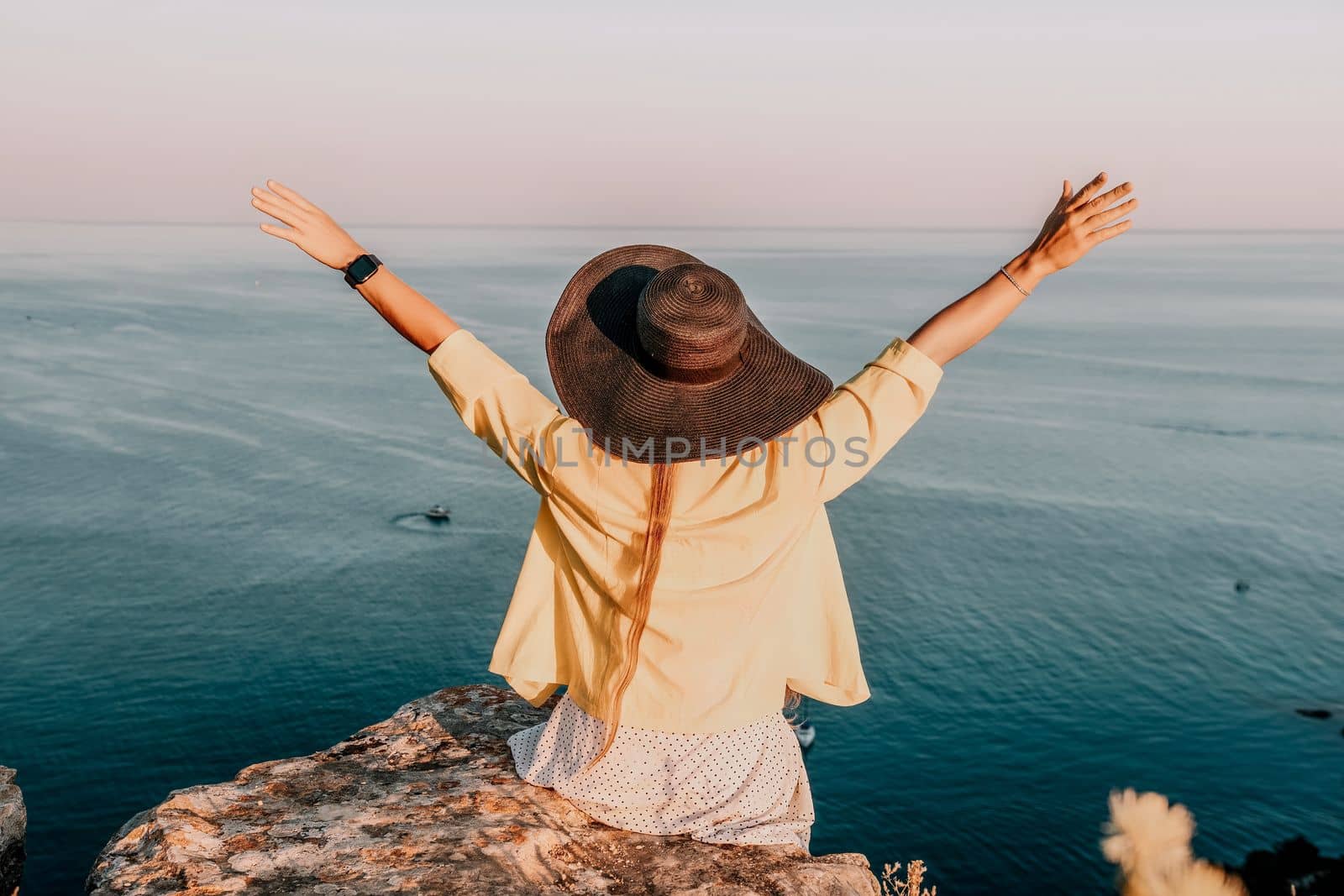 Portrait of happy young woman wearing summer black hat with large brim at beach on sunset. Sensual girl covering half face with hat on beach. Happy young woman smiling and looking at camera at sea. by panophotograph