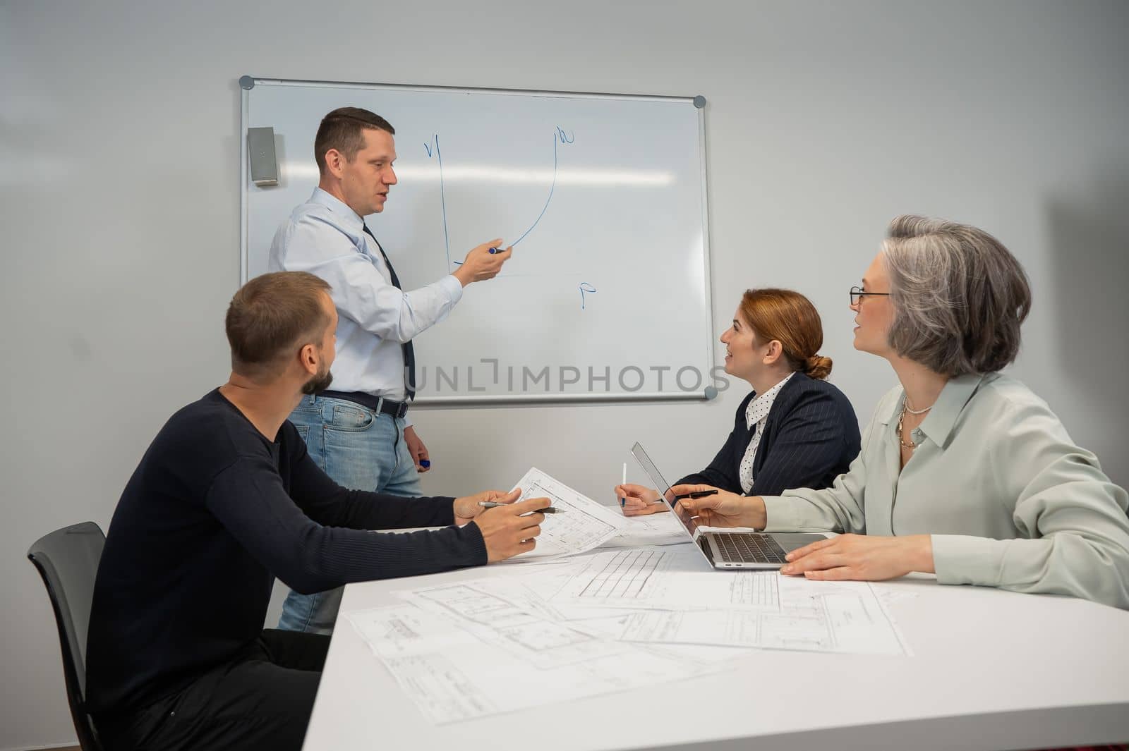 Caucasian man leading a presentation to colleagues at a white board. by mrwed54