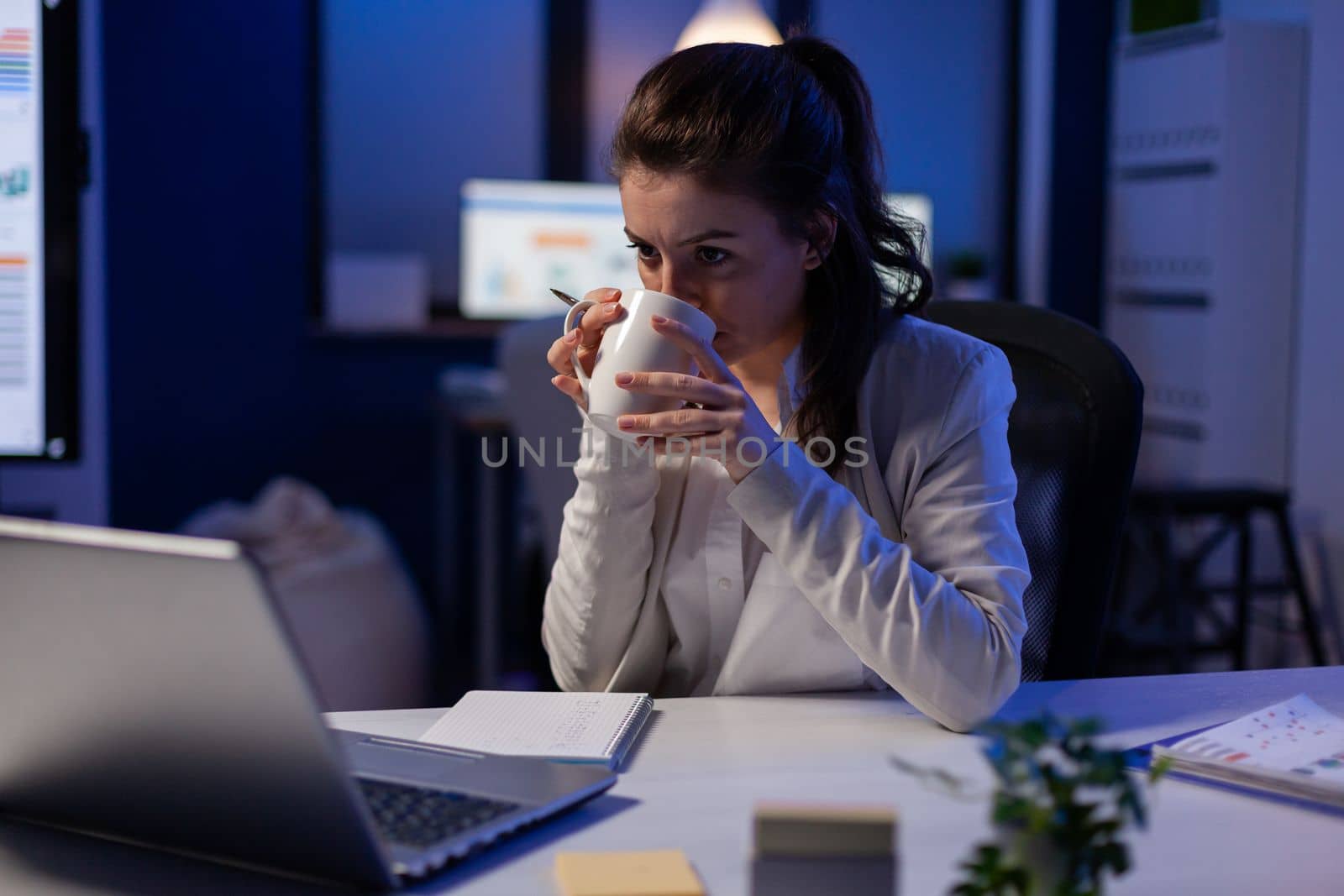 Manager having internet videocall conference sitting in professional start-up business office drinking cup of coffee. Woman talking on virtual meeting about increasing the percentage in marketing