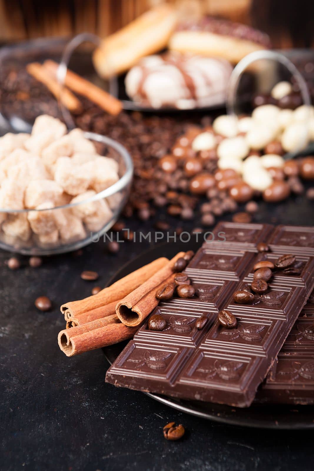 Chocolate tablets next to cinnamon rolls and other sweets and candies by DCStudio