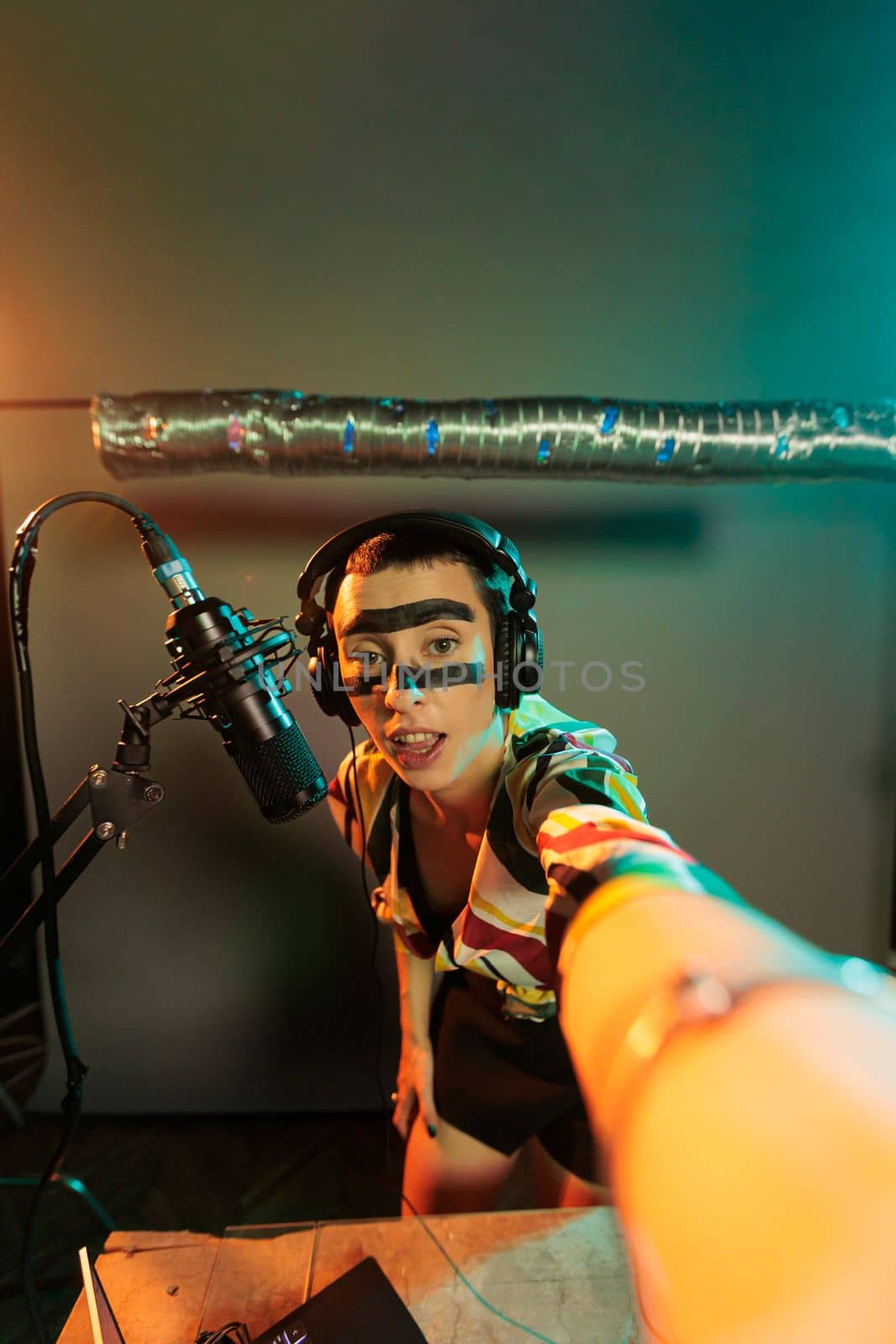 Cool performer using vinyl to mix music at turntables, doing remix of techno sounds at musical instrument. Mixing with audio mixer and headphones, doing dj record performance with microphone.