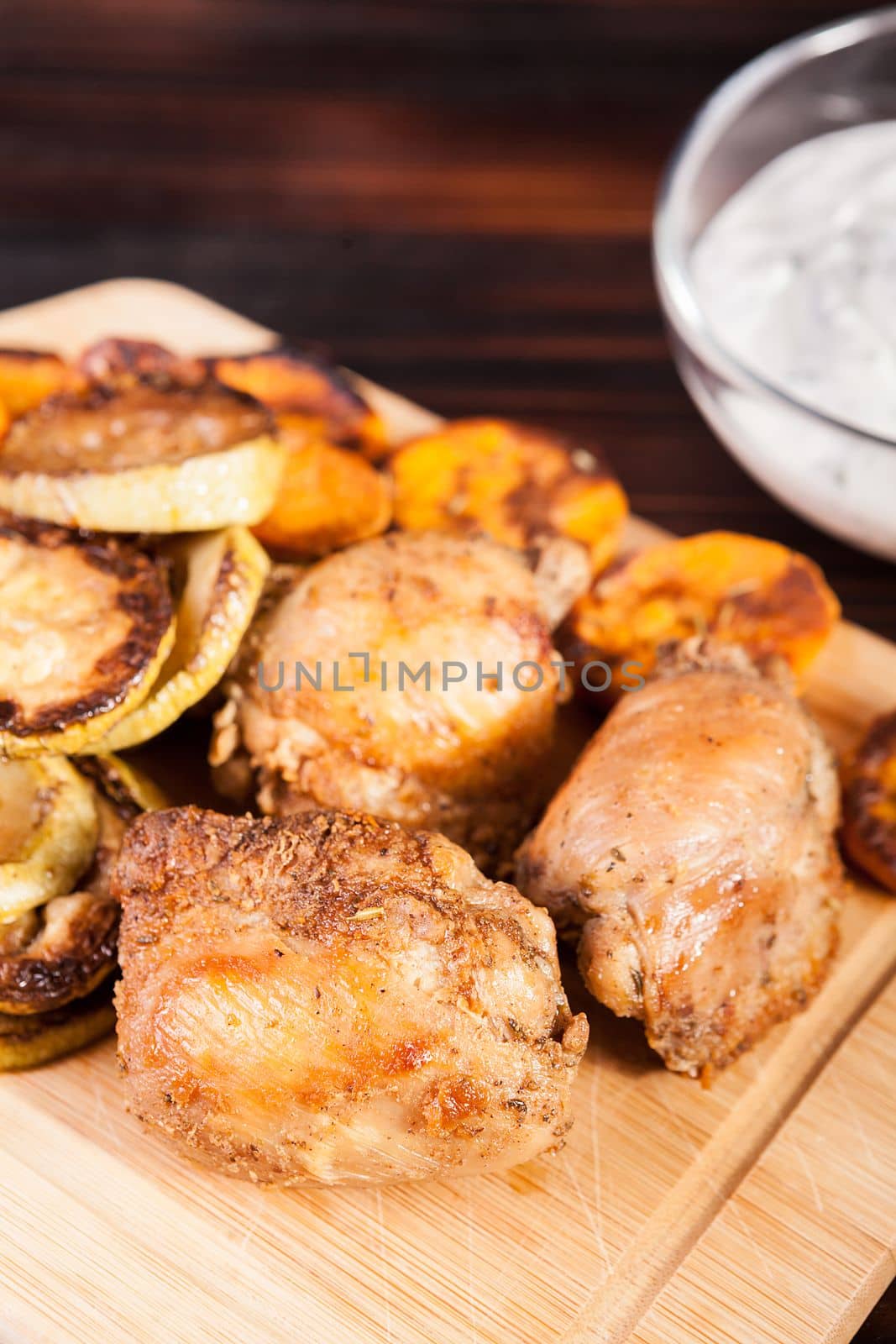 Healthy and delicious dinner made of fried chicken and grilled vegetables on wooden plate