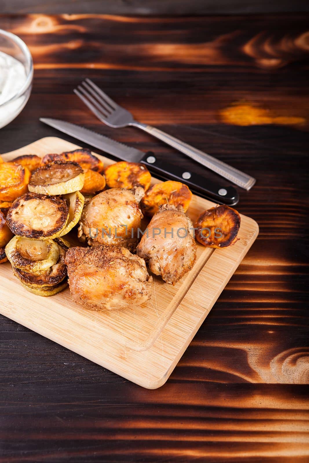 Fried chicken meat and grilled vegetables on wooden table