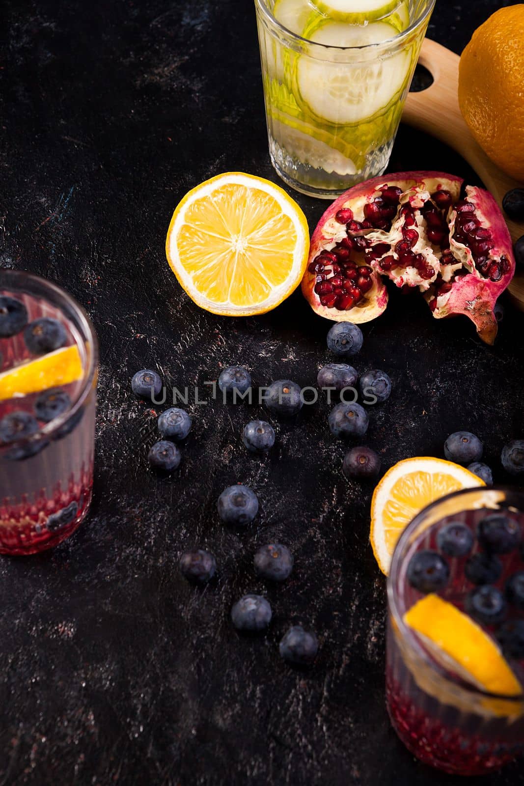 Lemons, pomegranate and berries on dark wooden background by DCStudio