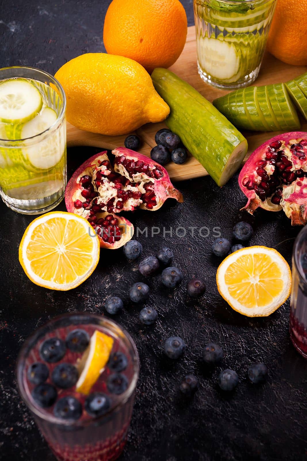 Lemons, pomegranate and berries on dark wooden background by DCStudio