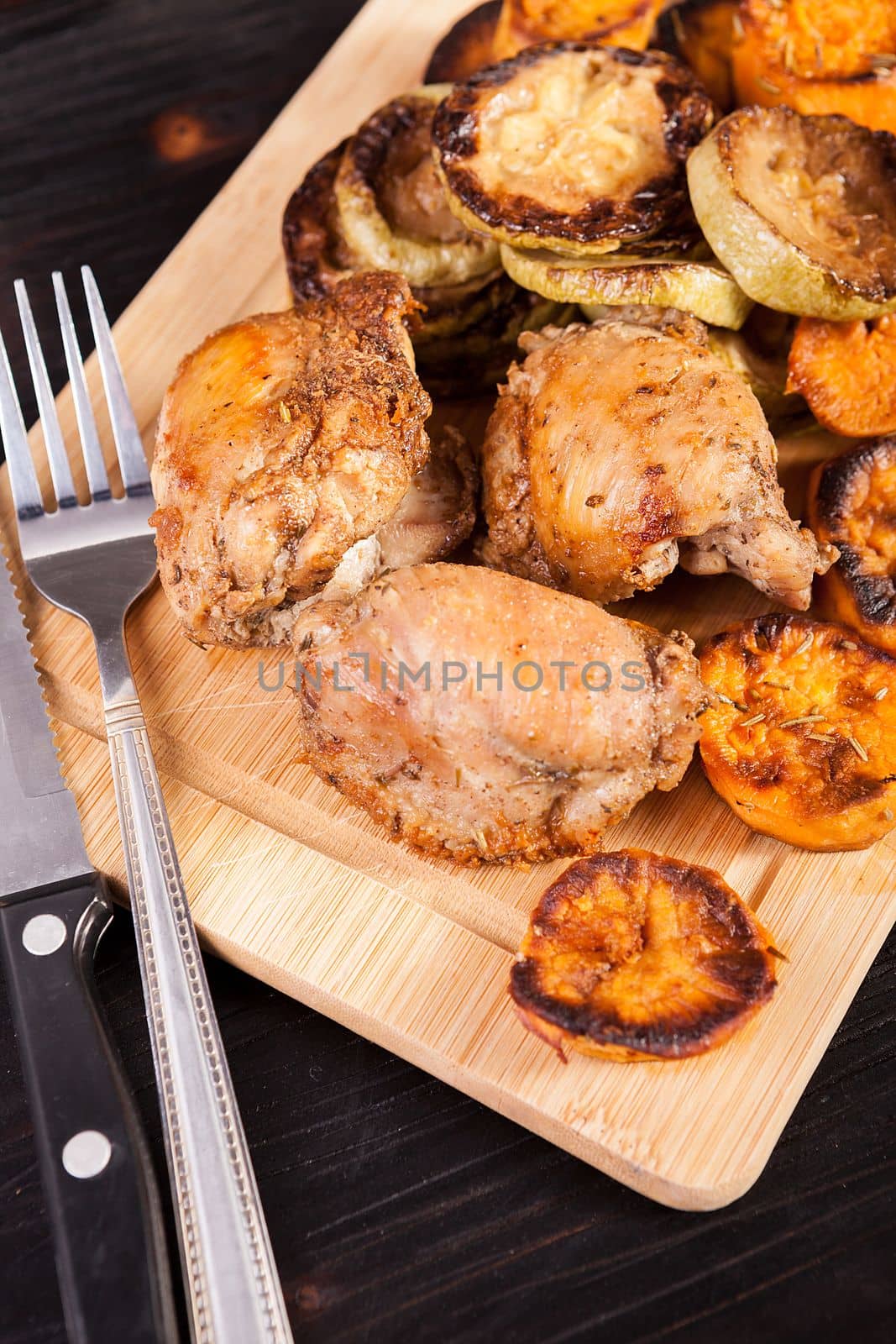 Wooden plate with fried chicken and grilled vegetables