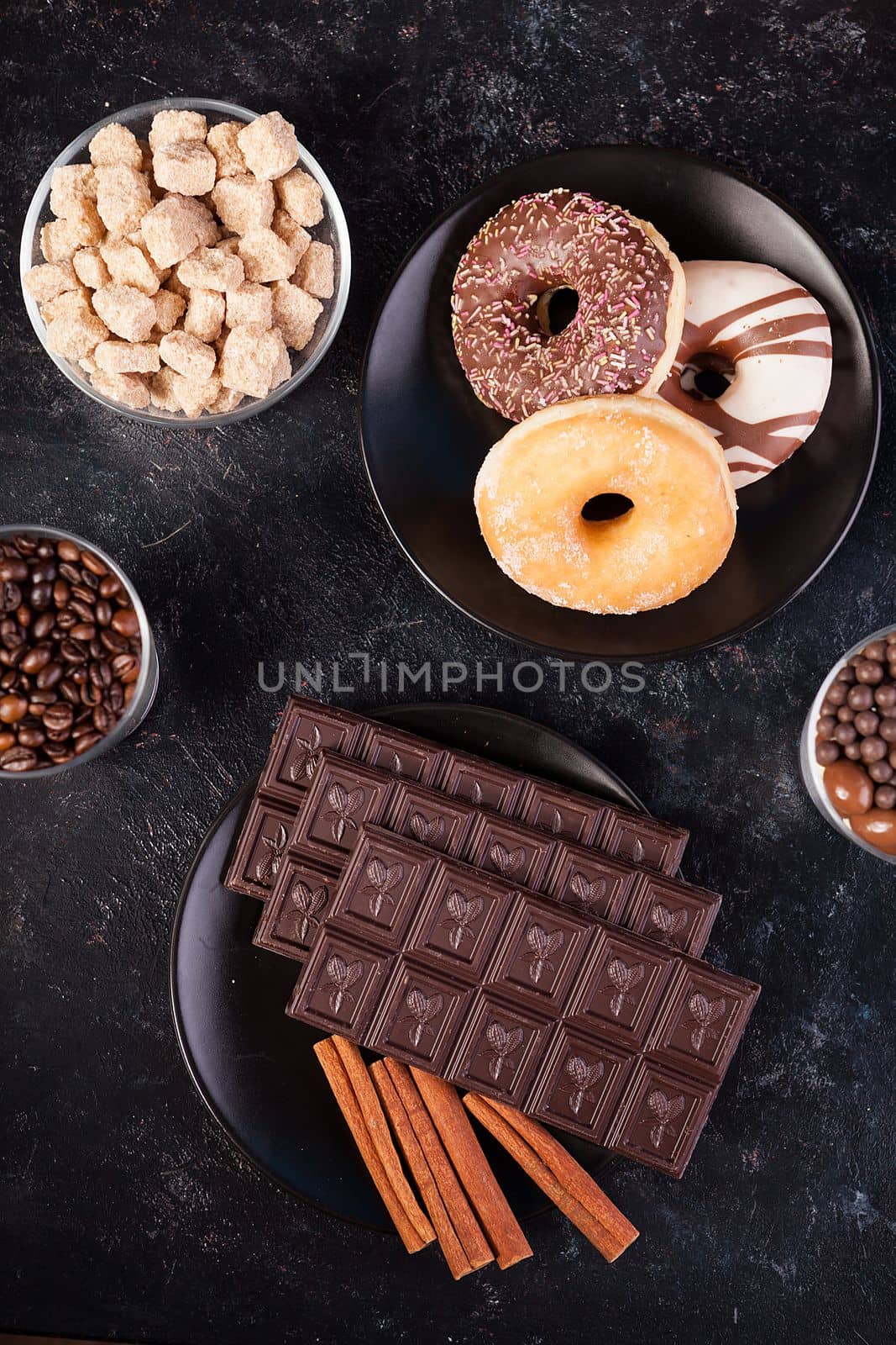 Top view of chocolate tablets, donuts, brown sugar with peanuts in chocolate and coffee beans by DCStudio