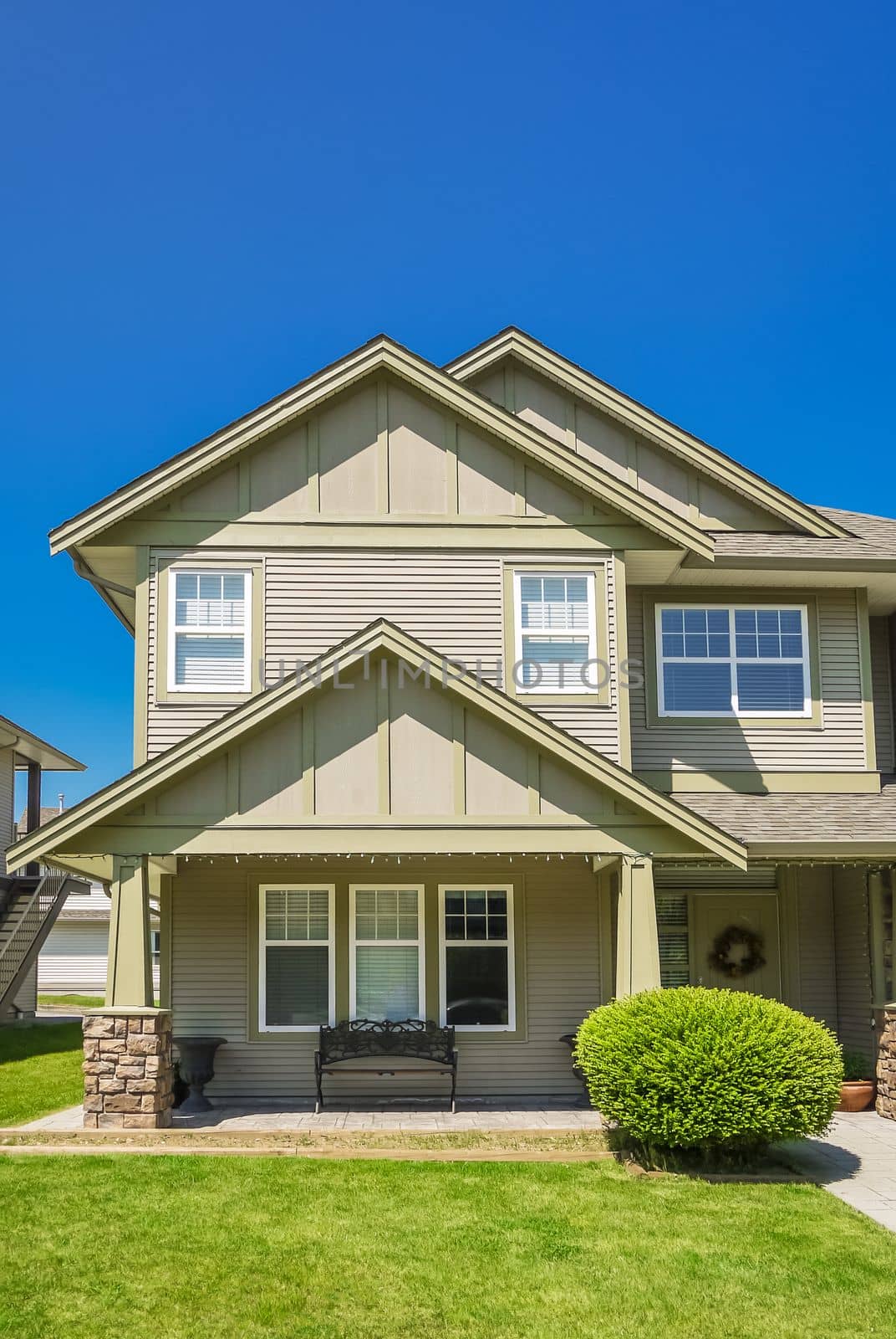 A perfect neighborhood. Suburban residential house with green lawn in front and blue sky background