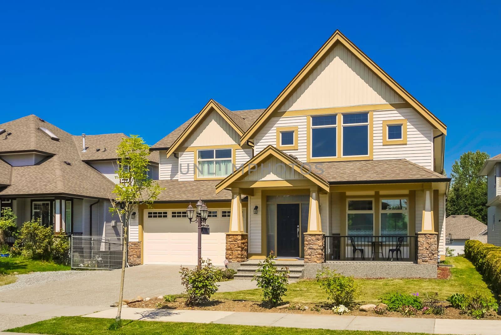 A perfect neighborhood. Big family house with concrete driveway to double size garage. Residential house with door steps to the entrance under the porch