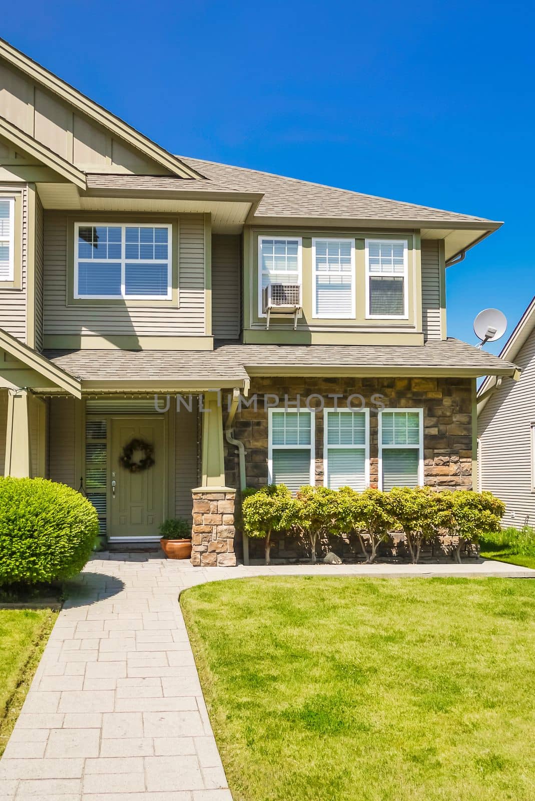 A perfect neighborhood. Entrance of family house with concrete pathway over green lawn to the front door