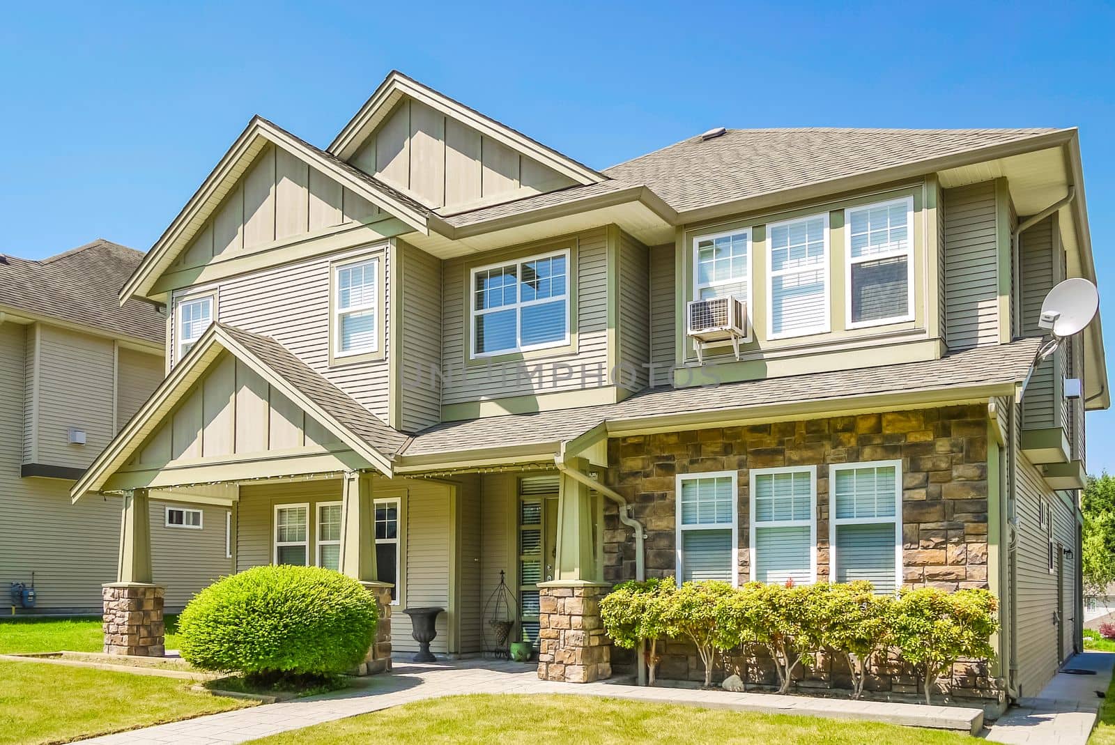 A perfect neighborhood. Luxury residential house with concrete pathway over front yard. Residential house with decorative bush at the entrance