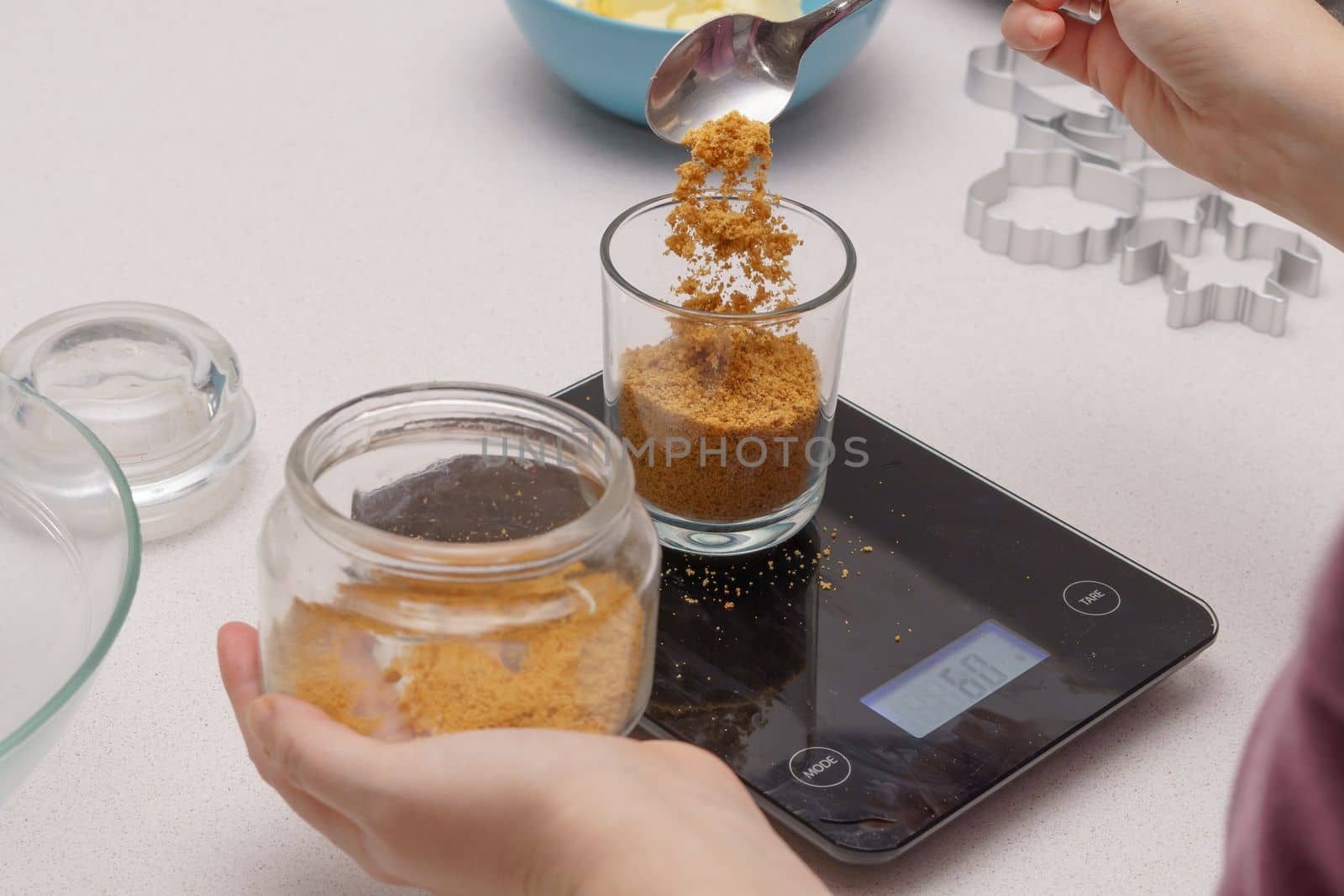 glass jar with brown sugar and a spoon in the background the hands of a woman preparing a cake