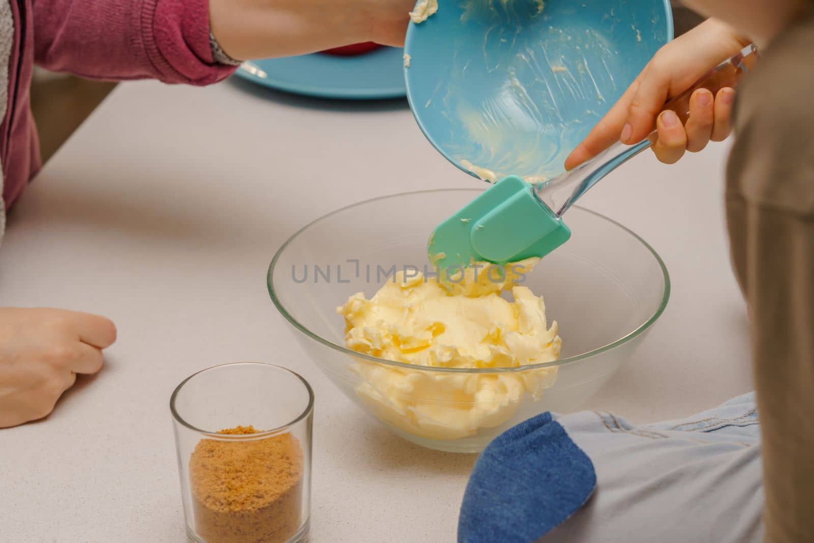 glass jar with brown sugar and a spoon in the background the hands of a woman preparing a cake