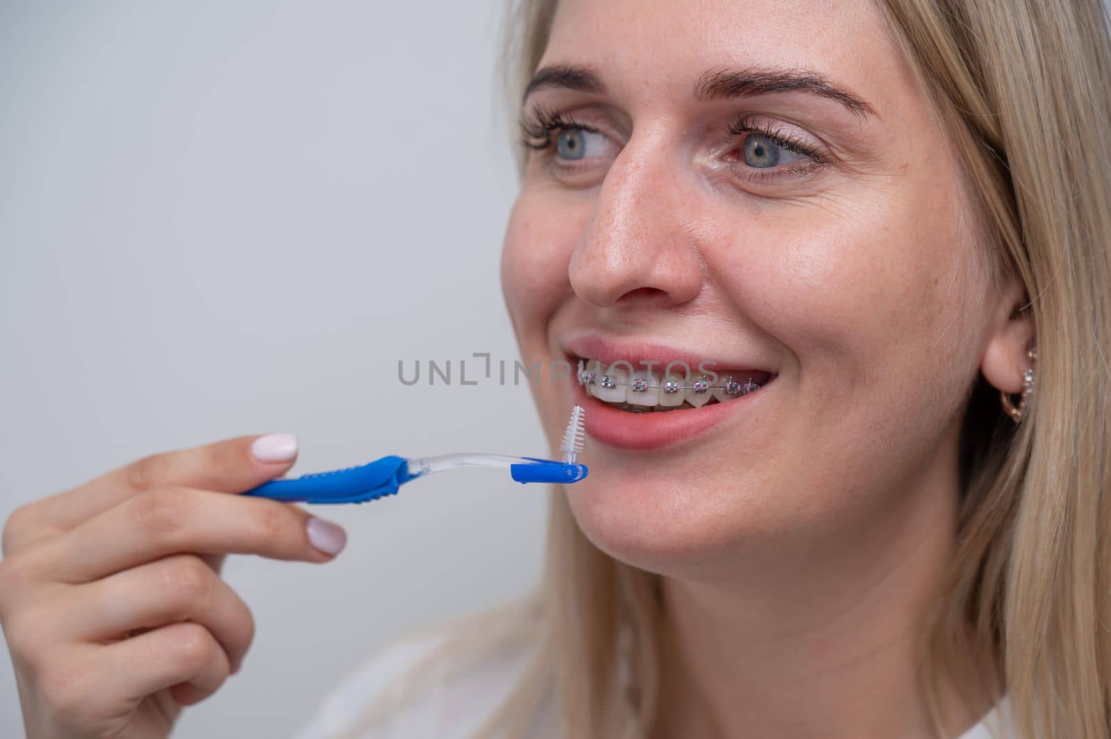 Caucasian woman cleaning her teeth with braces using a brush. by mrwed54