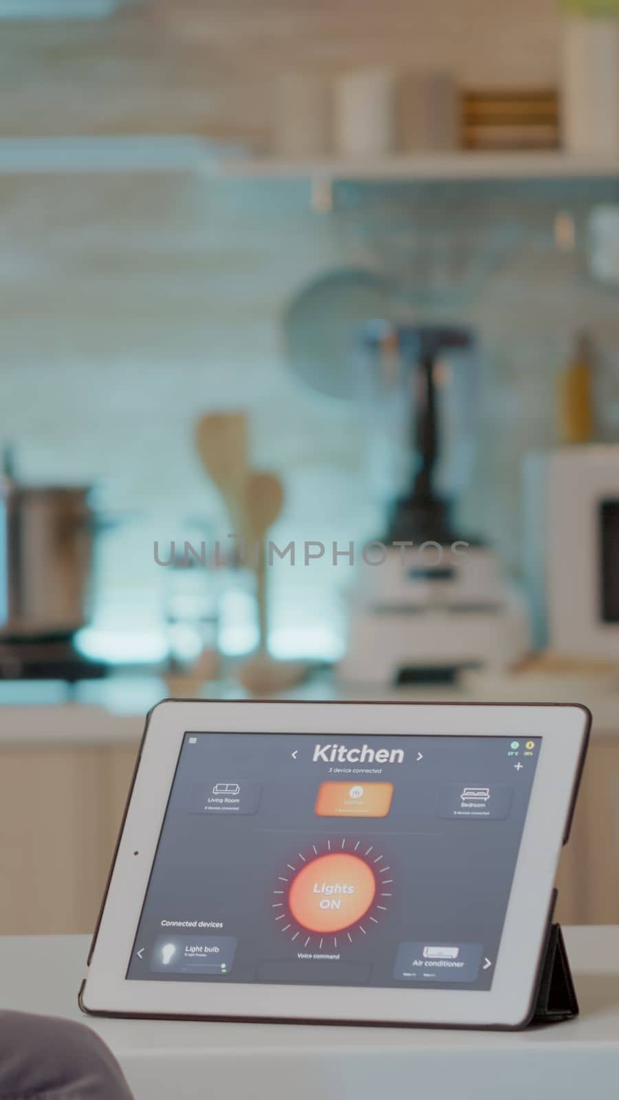 Man looking at tablet with intelligent software placed on kitchen table controlling light with high tech application. Person using notepad with smart home app in house automation system