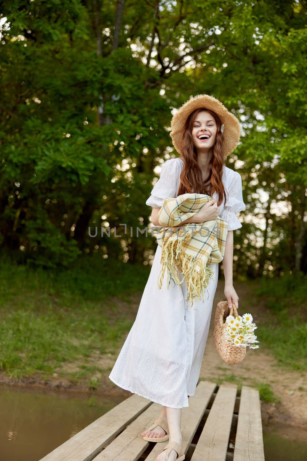 a woman in a light dress, with a plaid and a wicker basket in her hands, is spinning on the pier. High quality photo