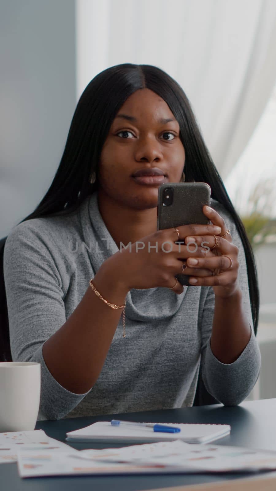 Black student holding phone in hands chatting with people browsing communication information by DCStudio