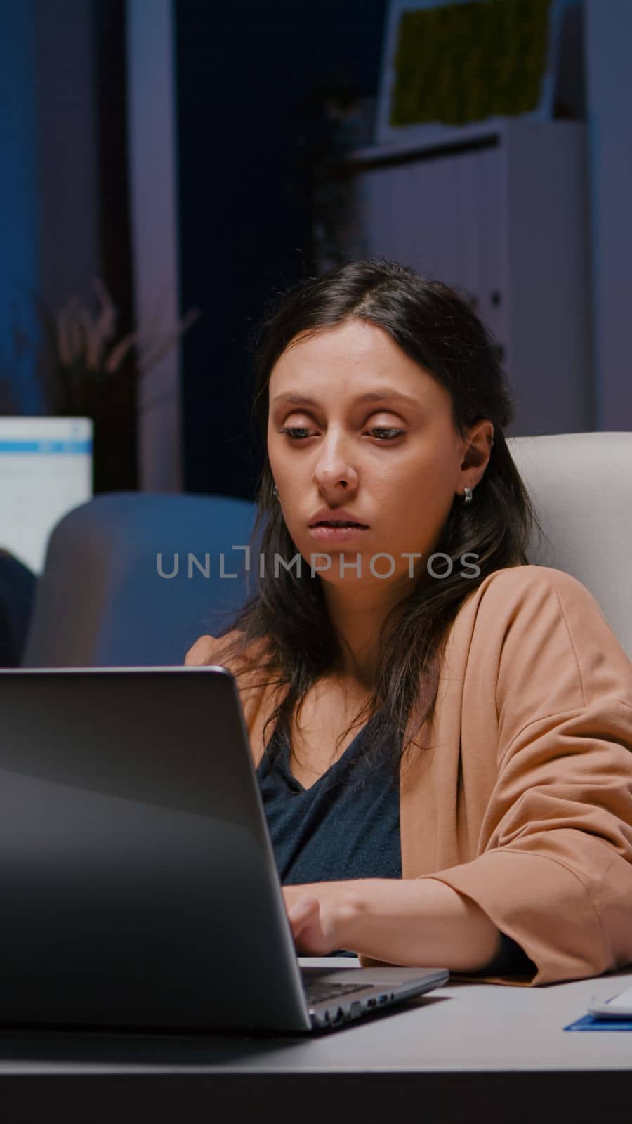 Workaholic entrepreneur woman sitting at desk table analysing financial graphics using laptop computer. Executive businesswoman planning marketing strategy working in startup business company office