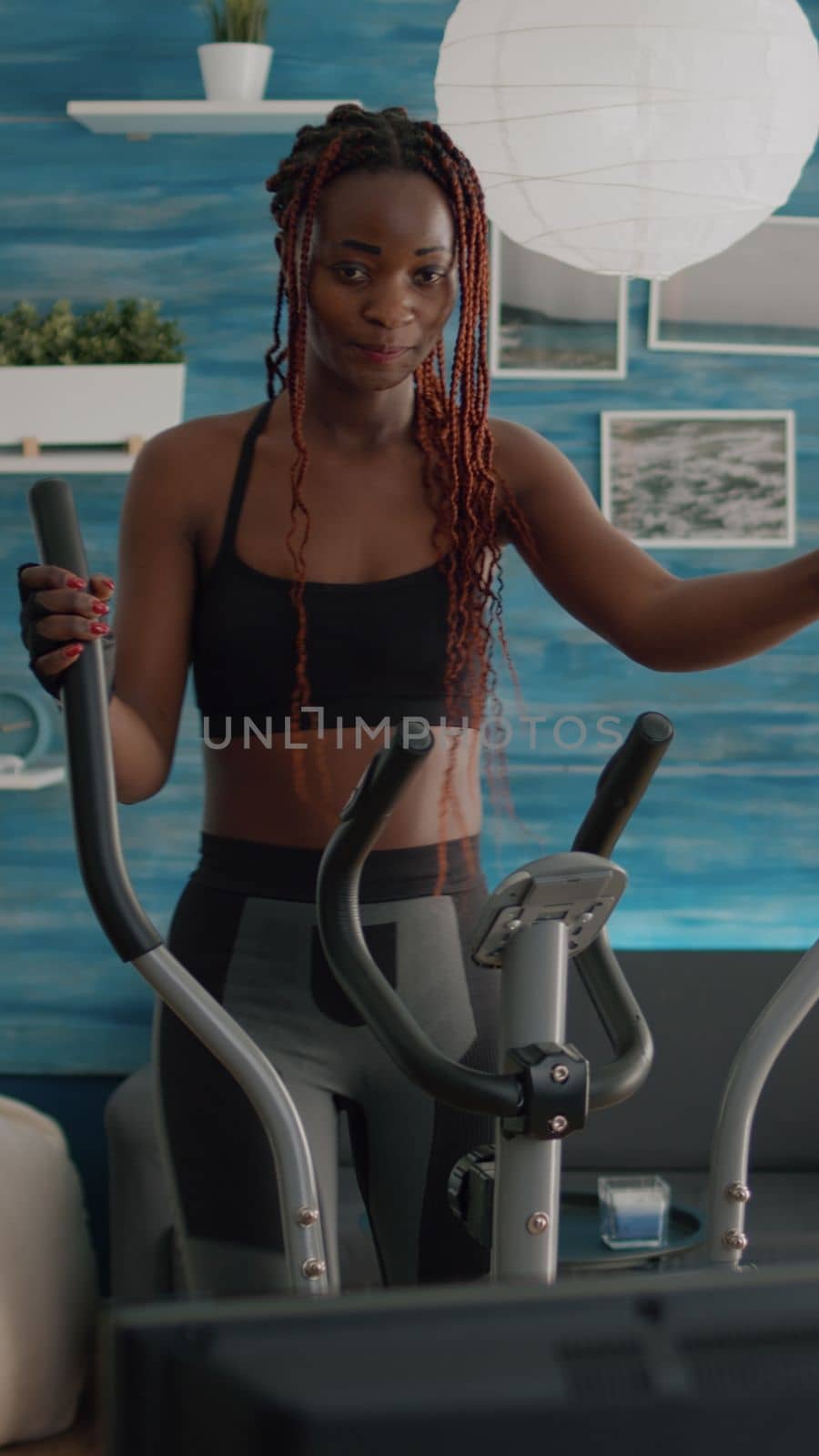 Black woman athletic training on elliptical bike practicing cardio sport by DCStudio