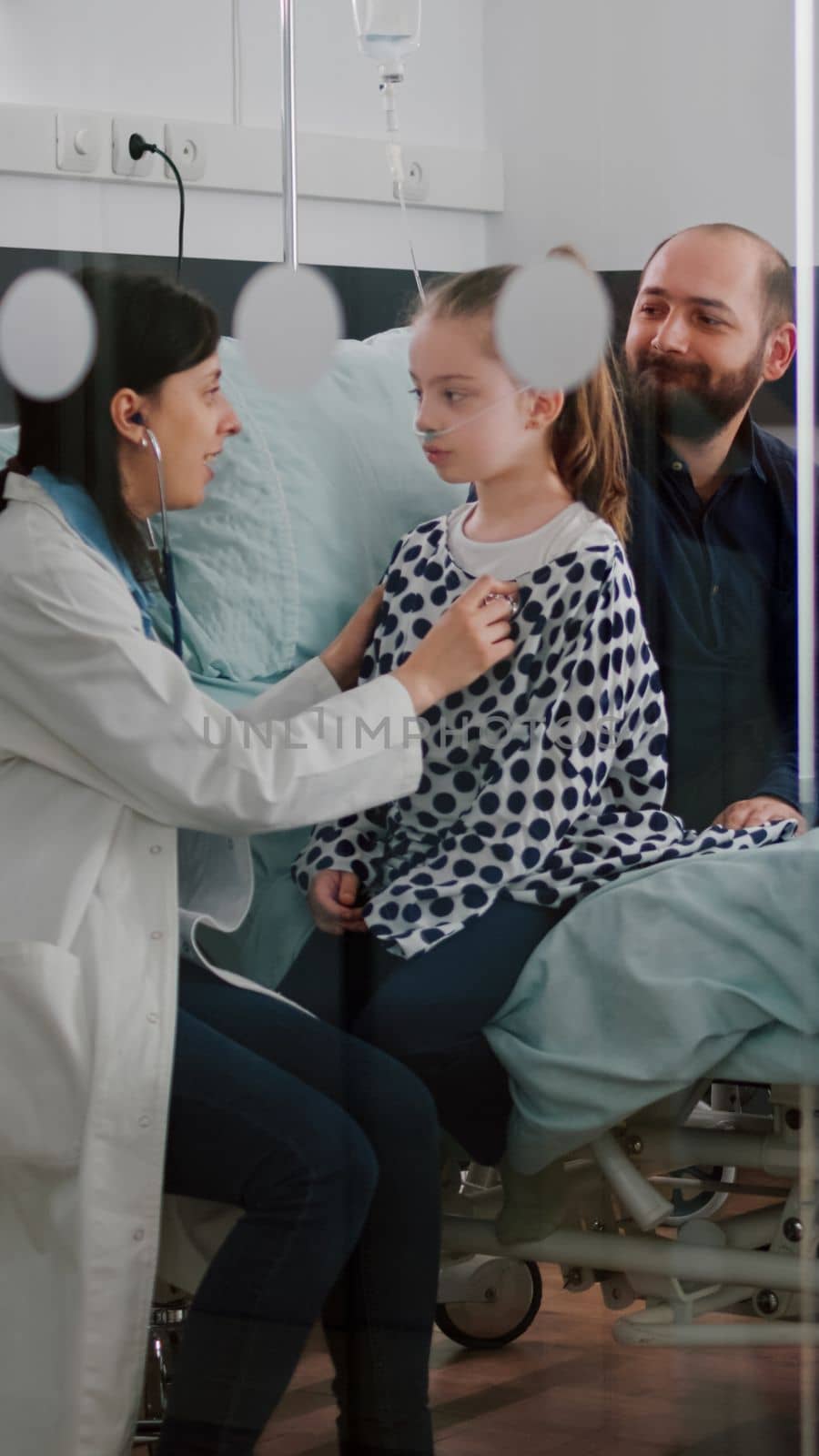 Paediatric woman doctor consulting sick patient listening heartbeat using medical stethoscope by DCStudio