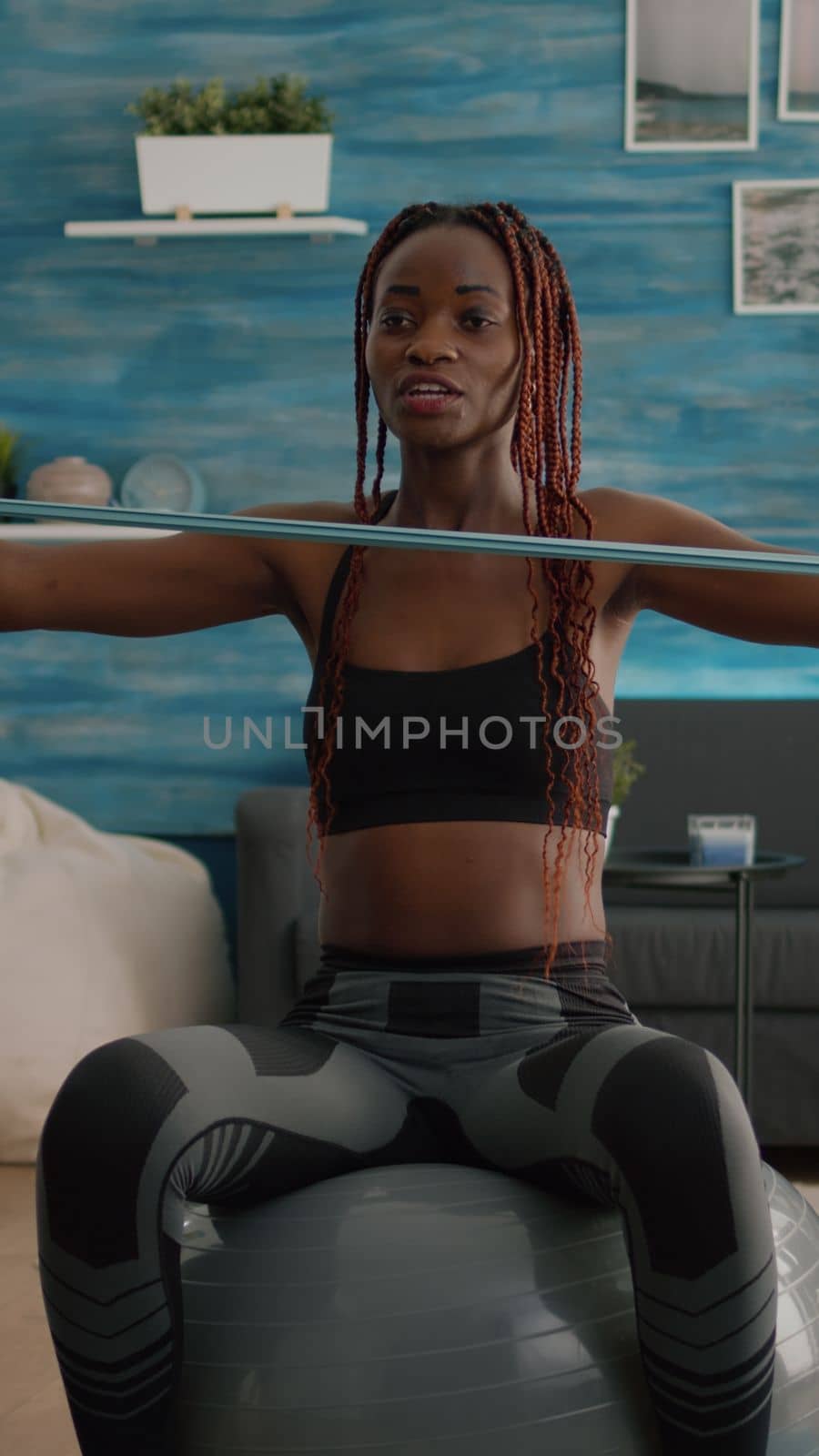 Athletic slim woman with black skin recording online yoga class using videocamera by DCStudio