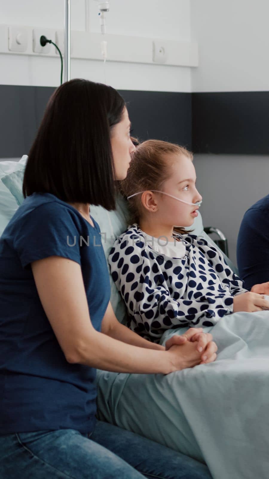 African american pediatric asisstant monitoring sick child discussing recovery treatment with parents during clinical examination in hospital ward. Black nurse writing disease symptoms on clipboard