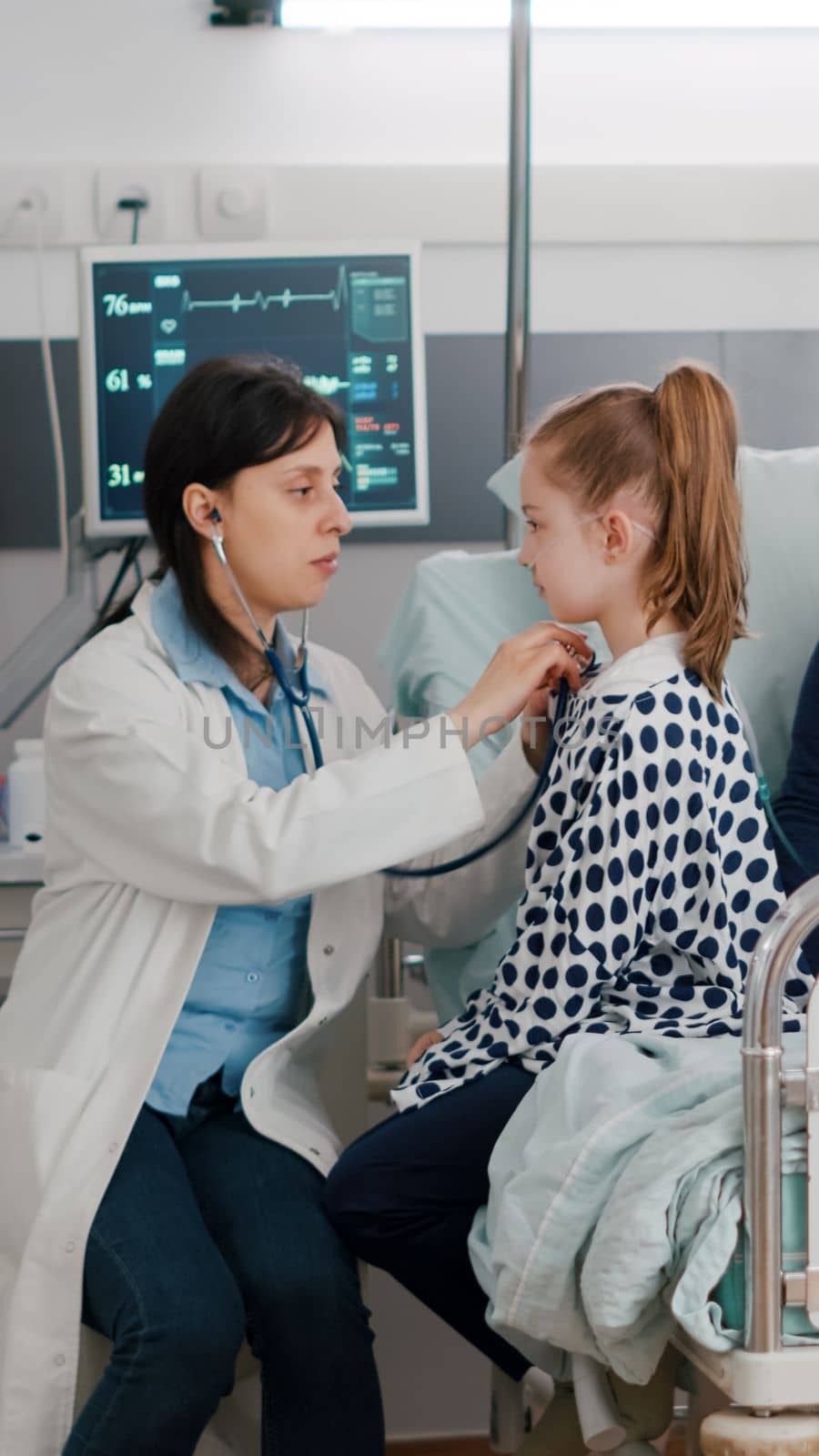 Pediatrician doctor consulting lungs listening heartbeat using medical stethoscope while african american nurse writing sickness medicaition treatment. Kid patient recovery in hospital ward