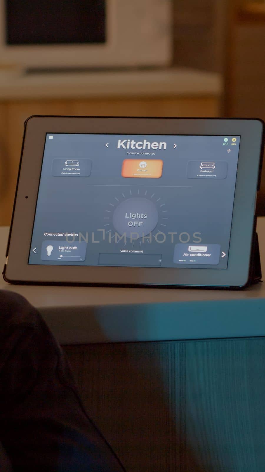 Man looking at tablet in house with automation lighting system, sitting in kitchen switching on bulbs using voice command. Person controlling lights using wifi gadget with smart home application