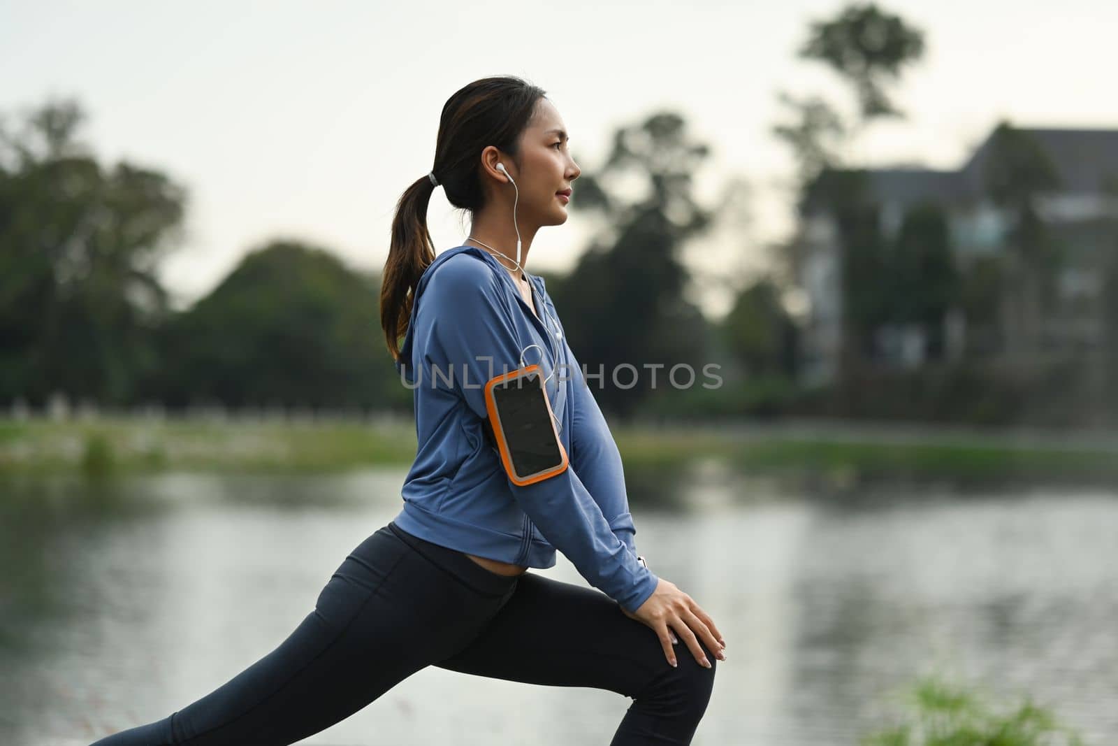 Sporty woman warming up, stretching her legs before morning workout. Fitness, sport and healthy lifestyle concept by prathanchorruangsak