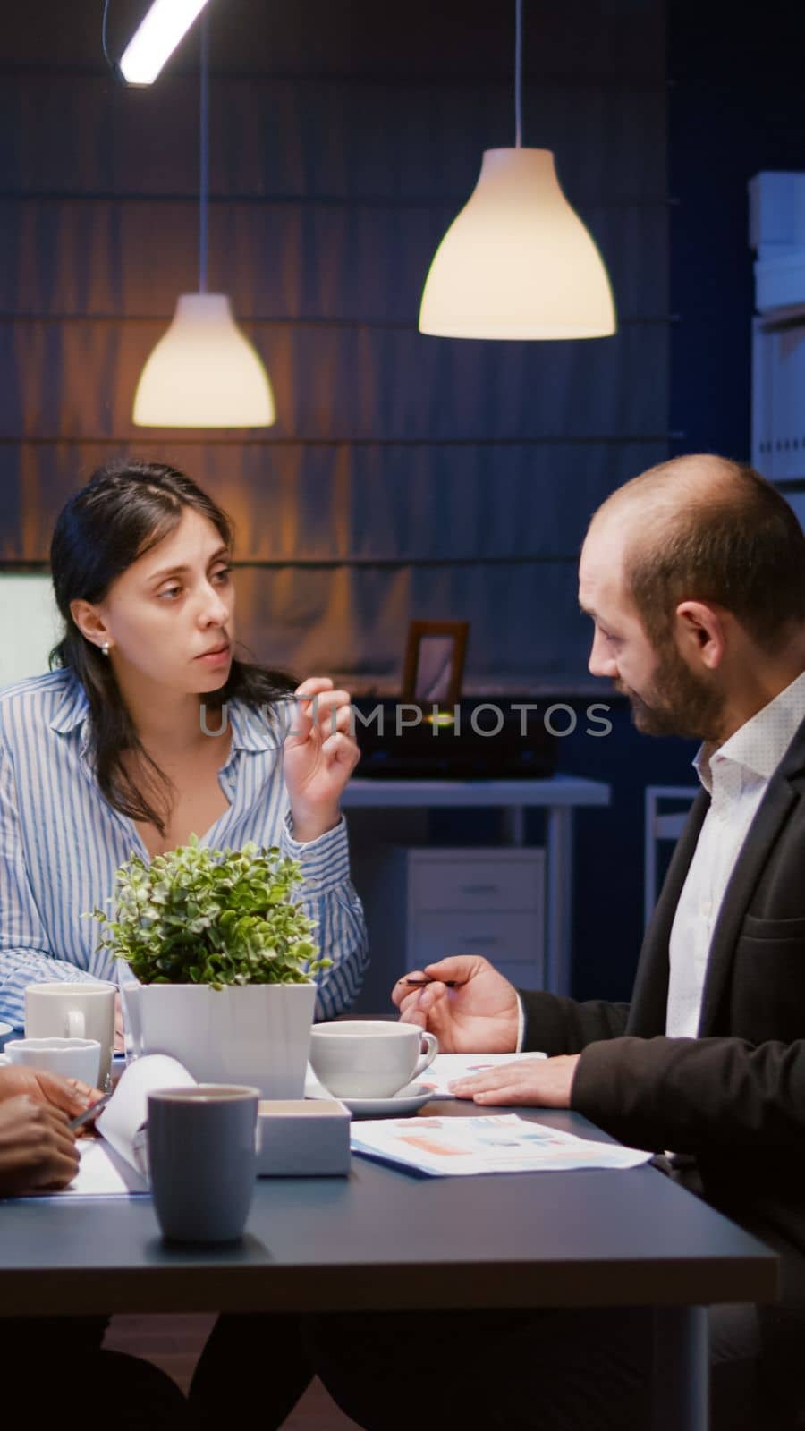 Executive manager woman explaining management statistics working at company strategy overtime in office meeting room. Diverse multi-ethnic businesspeople teamwork brainstorming ideas in evening