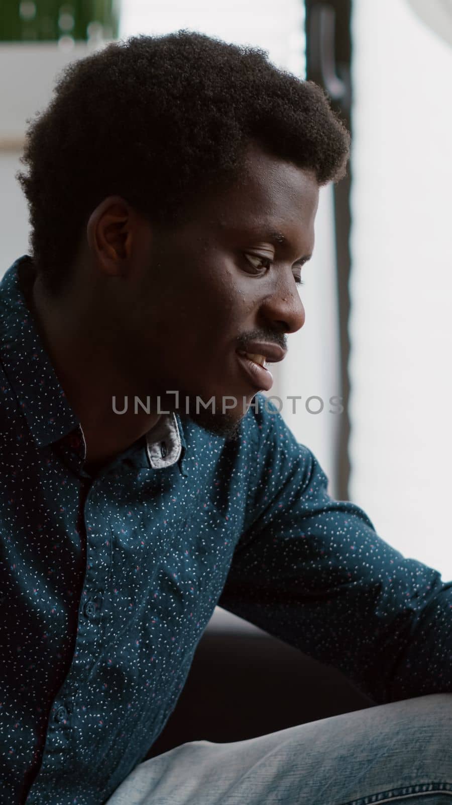 Happy smiling authentic african american guy on virtual communication using his phone to talk with relatives or work colleagues by DCStudio