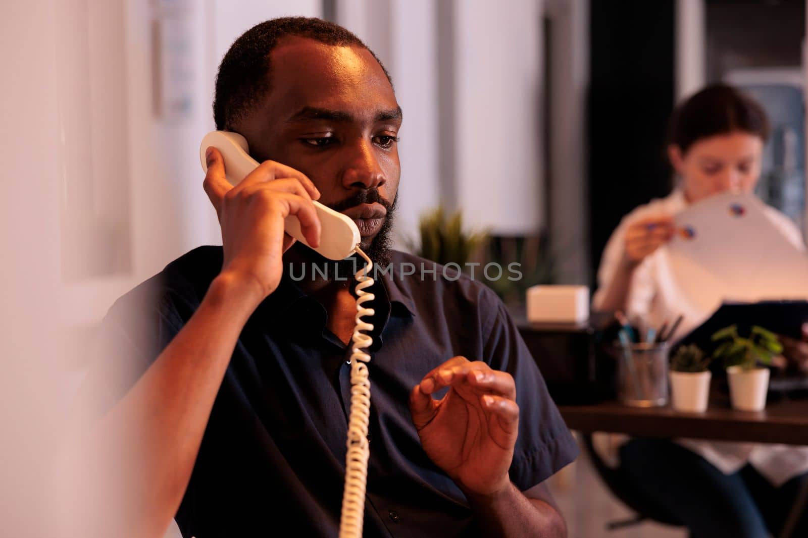 Project manager discussing startup strategy plan on landline phone by DCStudio