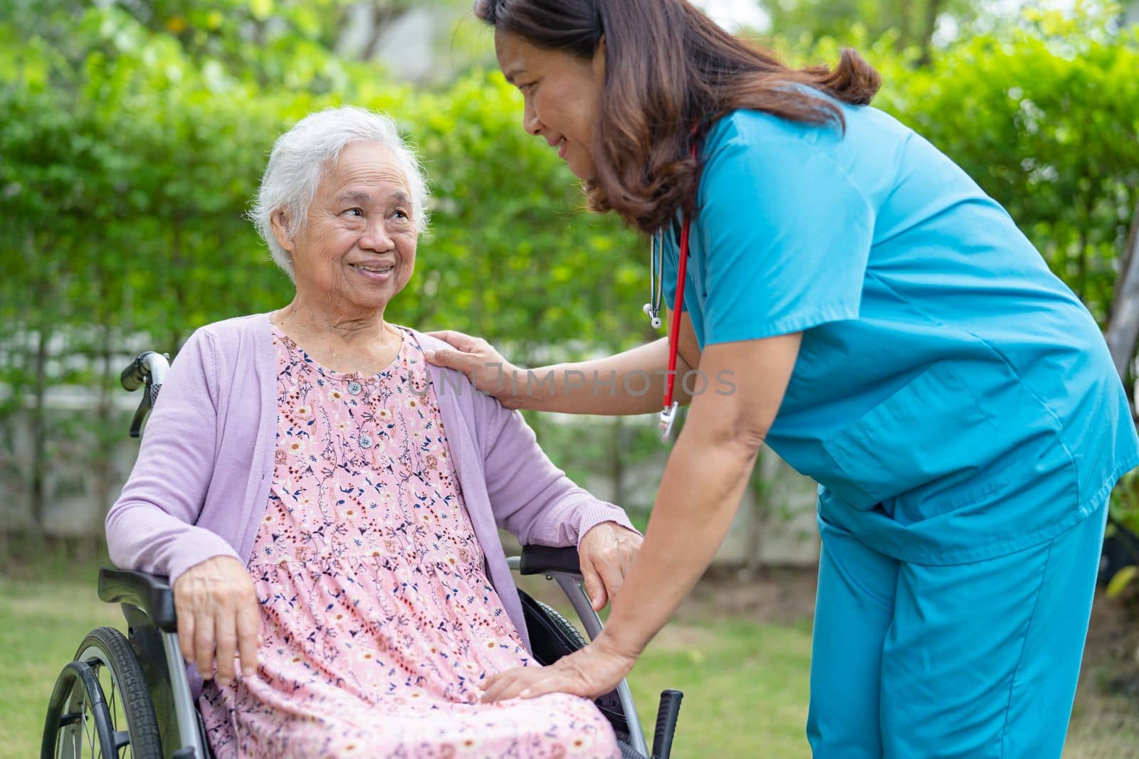 Doctor caregiver help and care Asian senior or elderly old lady woman patient sitting on wheelchair in park at nursing hospital, healthy strong medical concept by pamai