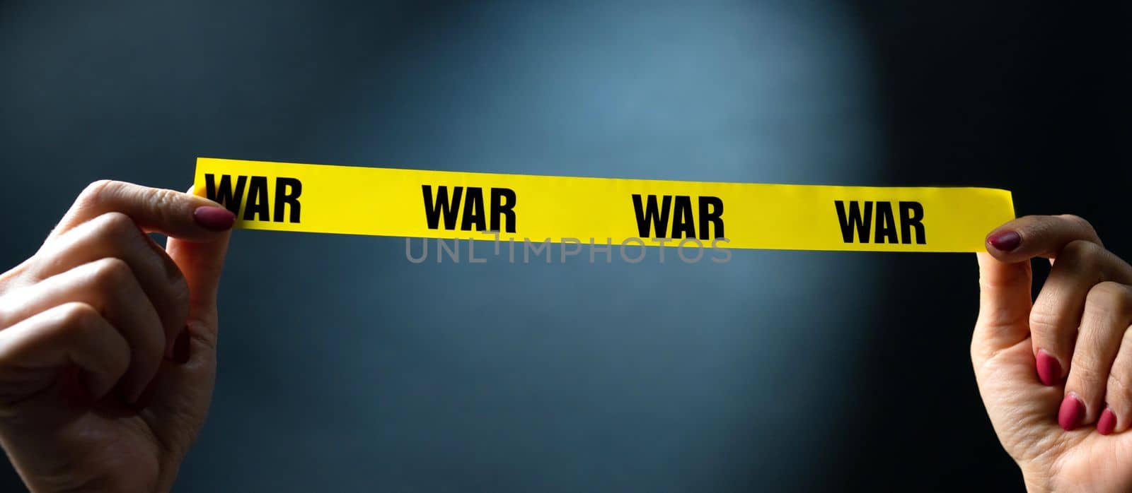 Hands holding yellow tape with war text as symbol of safety and stop conflict. Concept of invasion, danger and truth