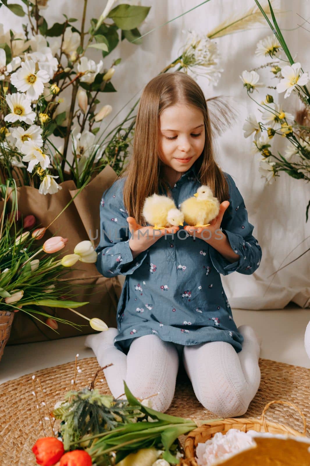 Two girls in a beautiful Easter photo zone with flowers, eggs, chickens and Easter bunnies. Happy Easter holiday