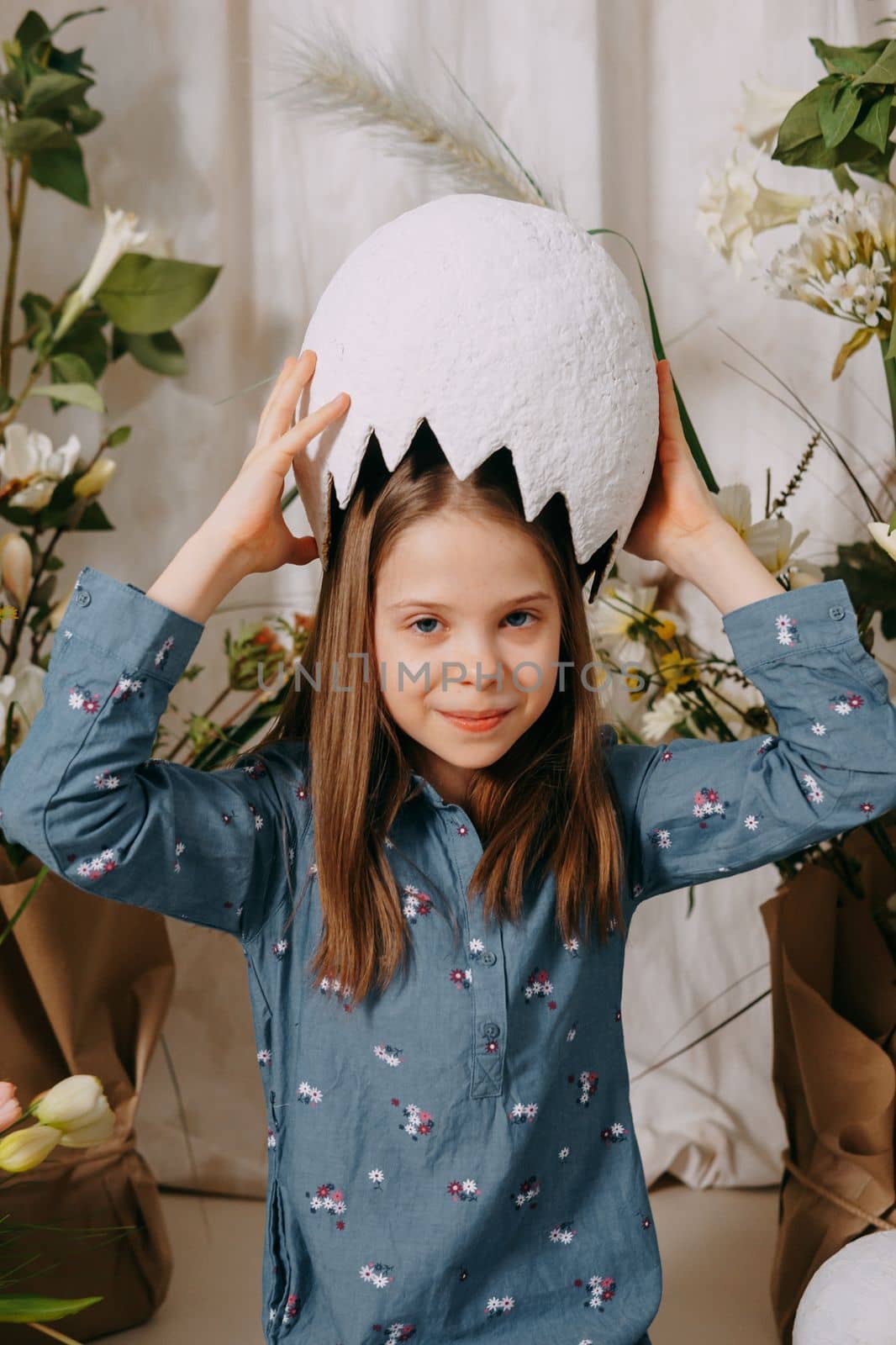 Two girls in a beautiful Easter photo zone with flowers, eggs, chickens and Easter bunnies. Happy Easter holiday