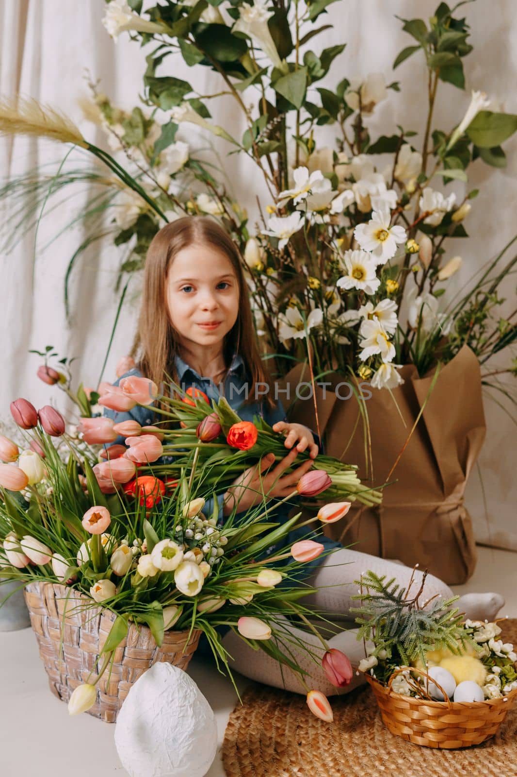 Two girls in a beautiful Easter photo zone with flowers, eggs, chickens and Easter bunnies. Happy Easter holiday