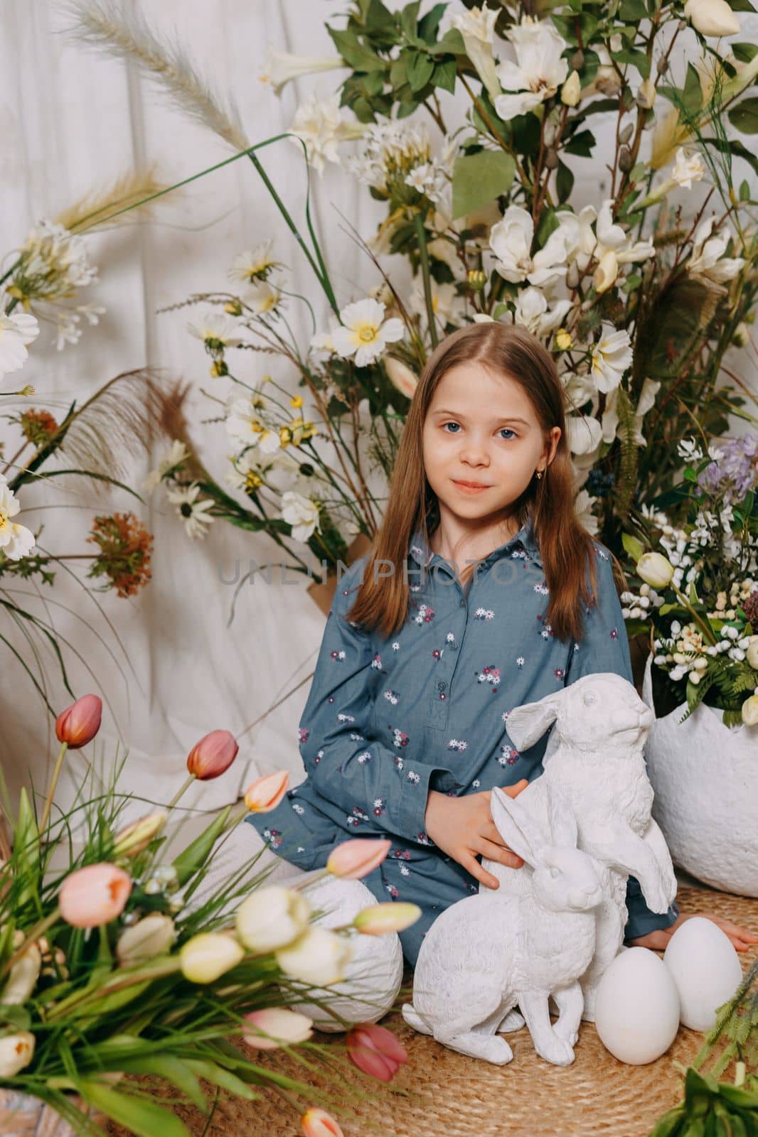 Two girls in a beautiful Easter photo zone with flowers, eggs, chickens and Easter bunnies. Happy Easter holiday