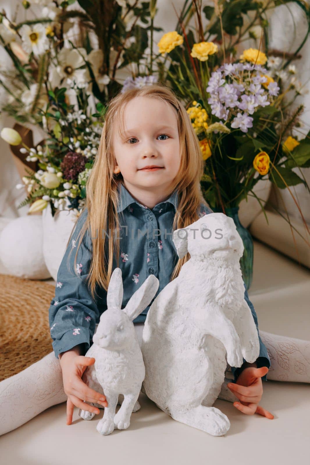 Two girls in a beautiful Easter photo zone with flowers, eggs, chickens and Easter bunnies. Happy Easter holiday. by Annu1tochka