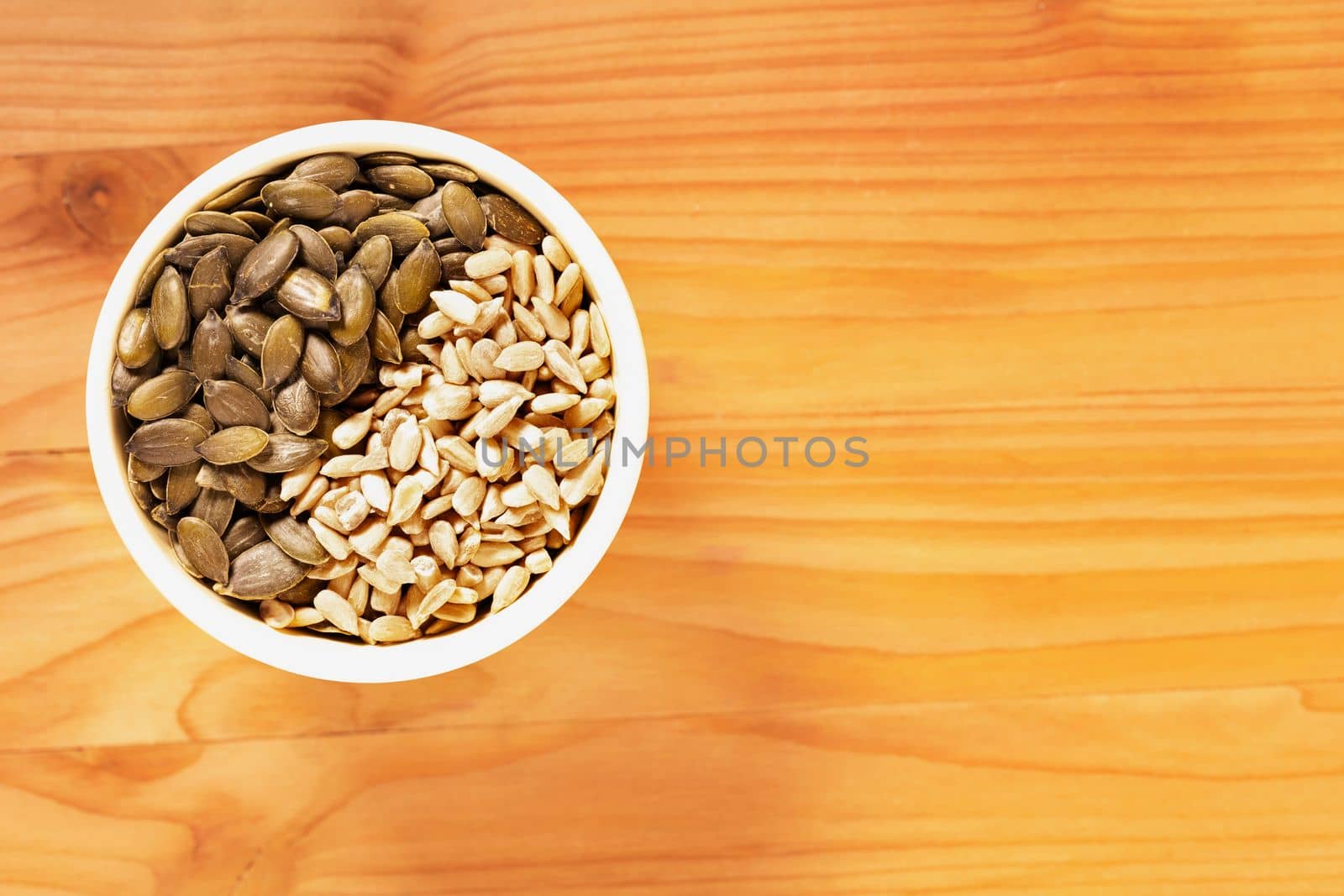 Pumpkin and sunflower  seedsin bowl on wooden table , healthy eating