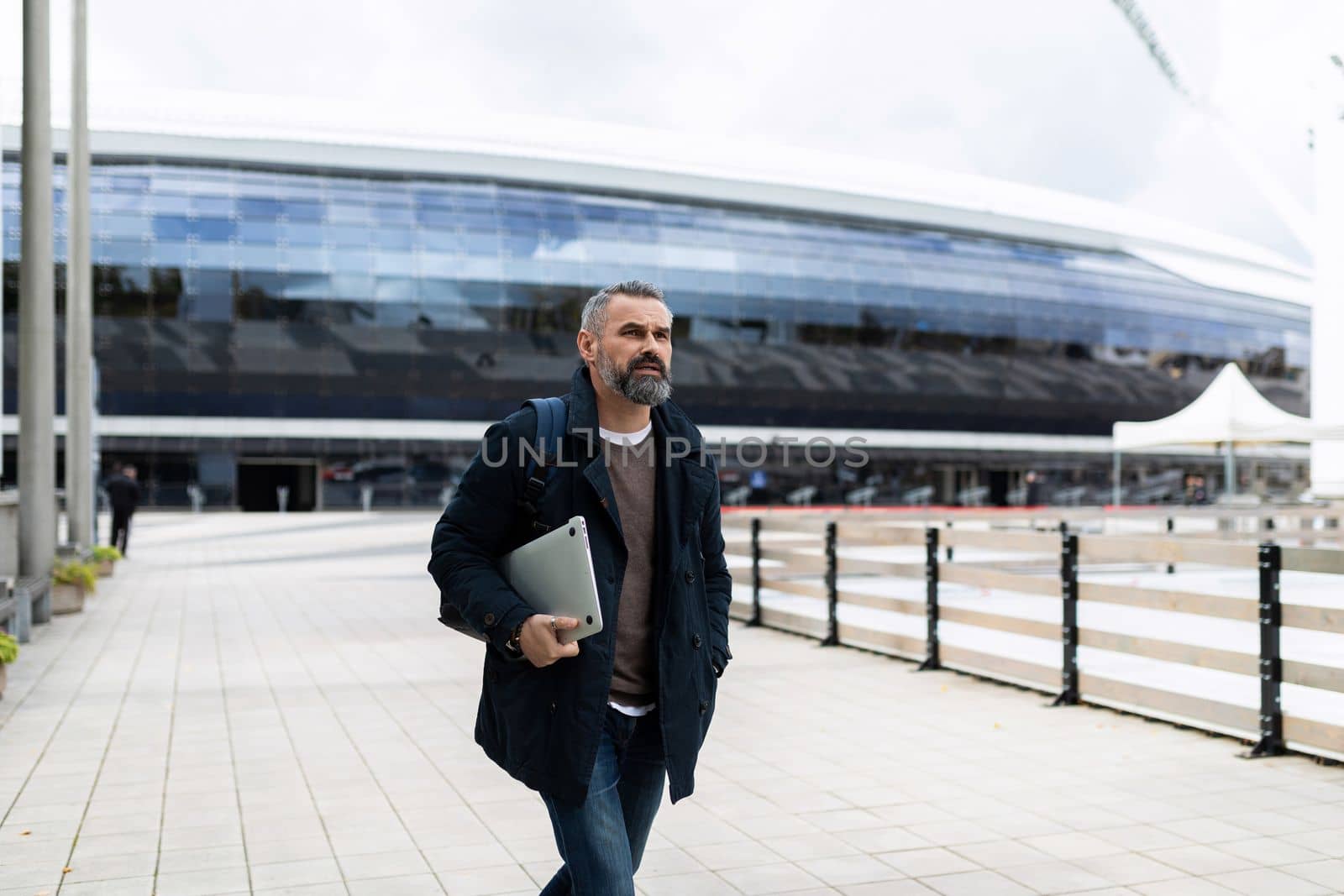 mature man with a laptop on the background of a modern city building.