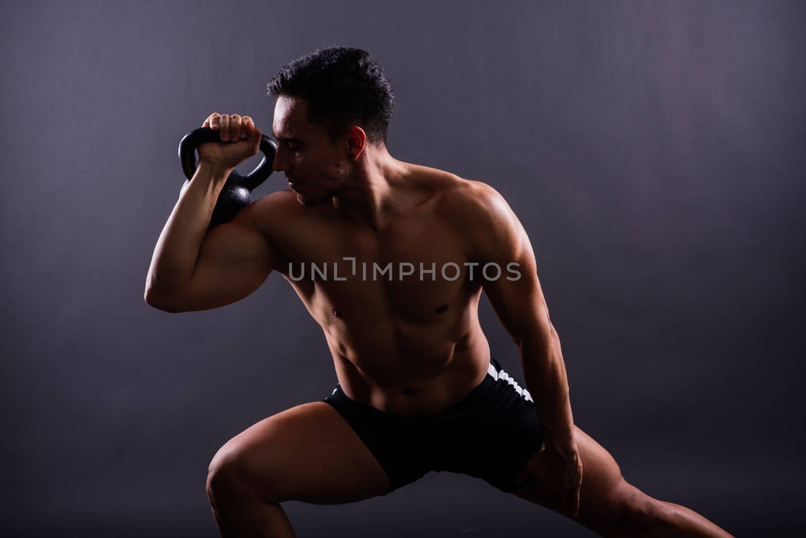 Handsome muscular man holding kettle bell with copy space. Hispanic male athlete by Zelenin