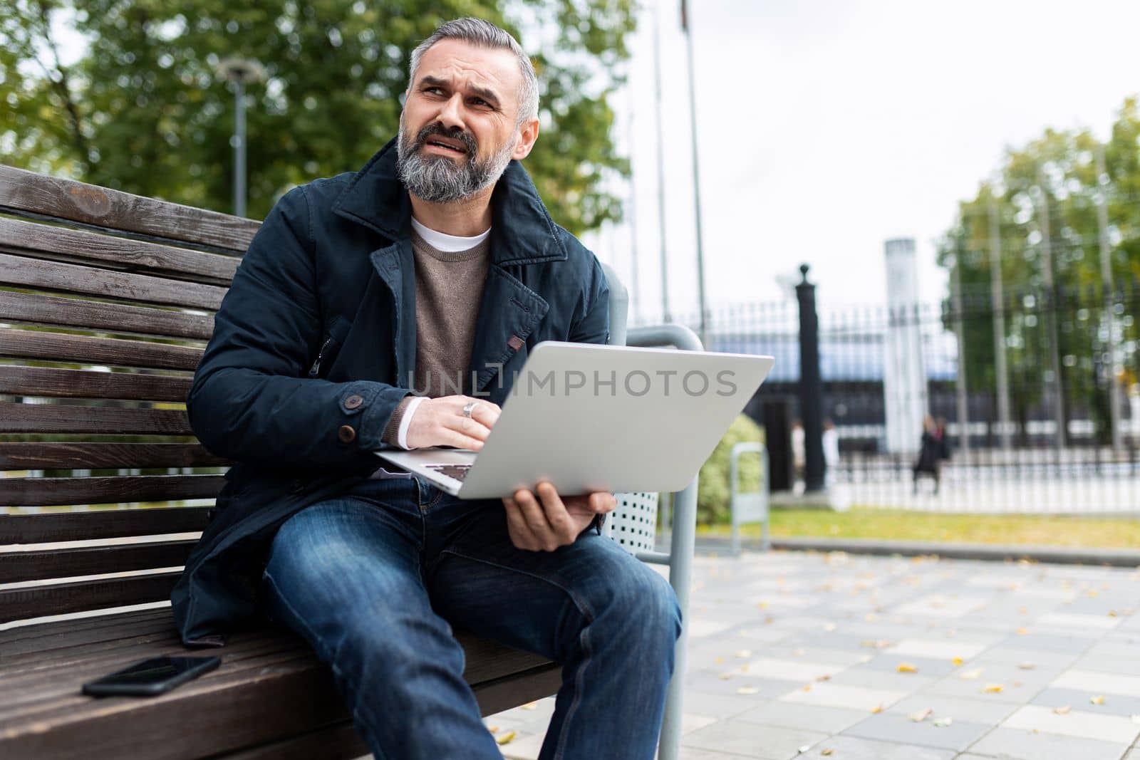 Gray-haired mature man with laptop outside by TRMK