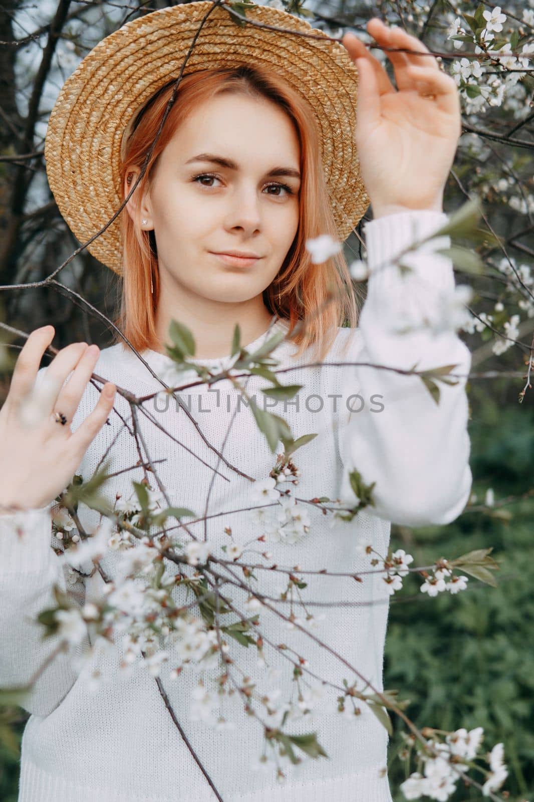 Portrait of a woman in a straw hat in a cherry blossom. Free outdoor recreation, spring blooming garden
