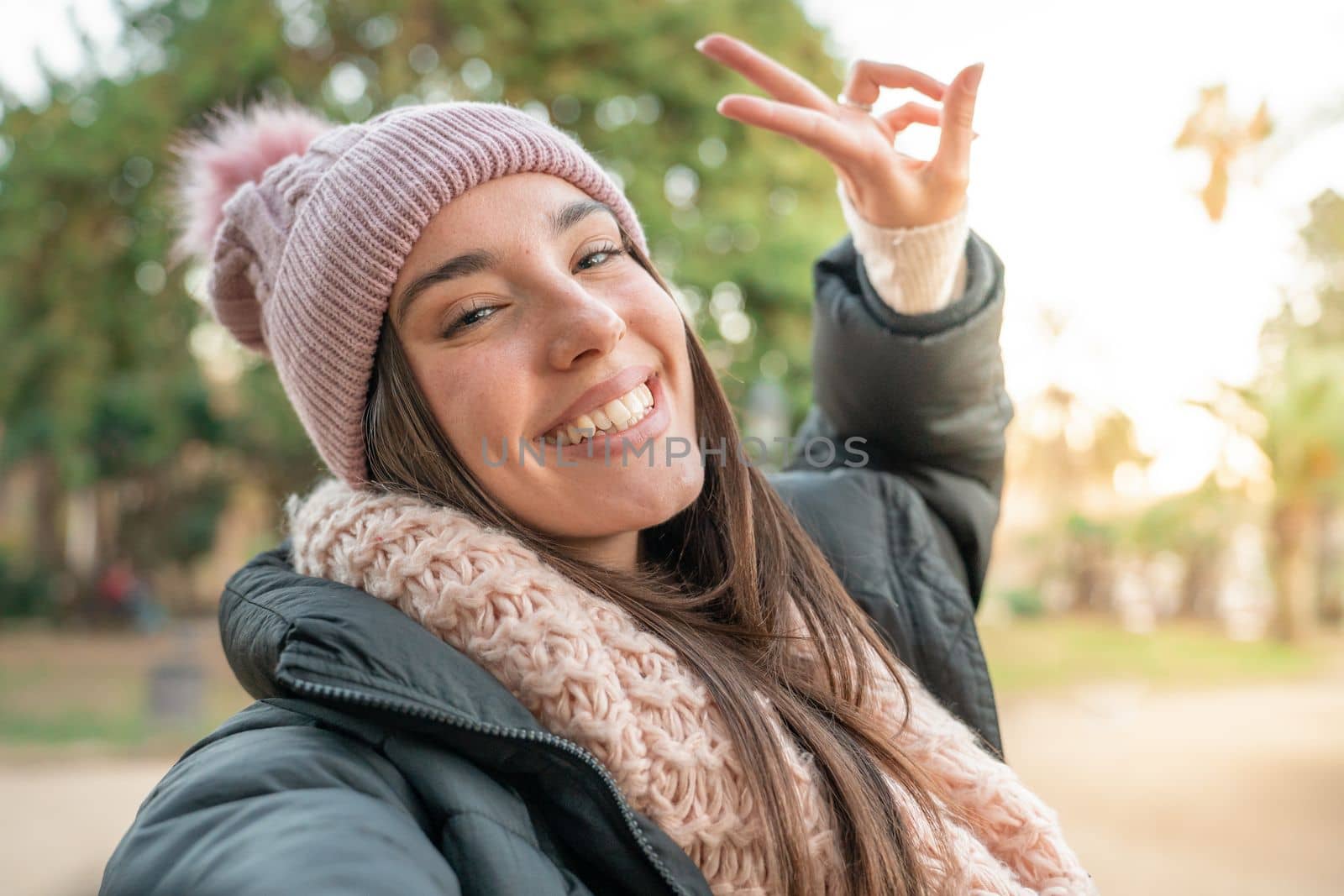 Young beautiful woman smiling taking selfie photo at university campus. Trendy girl with winter hat. by PaulCarr