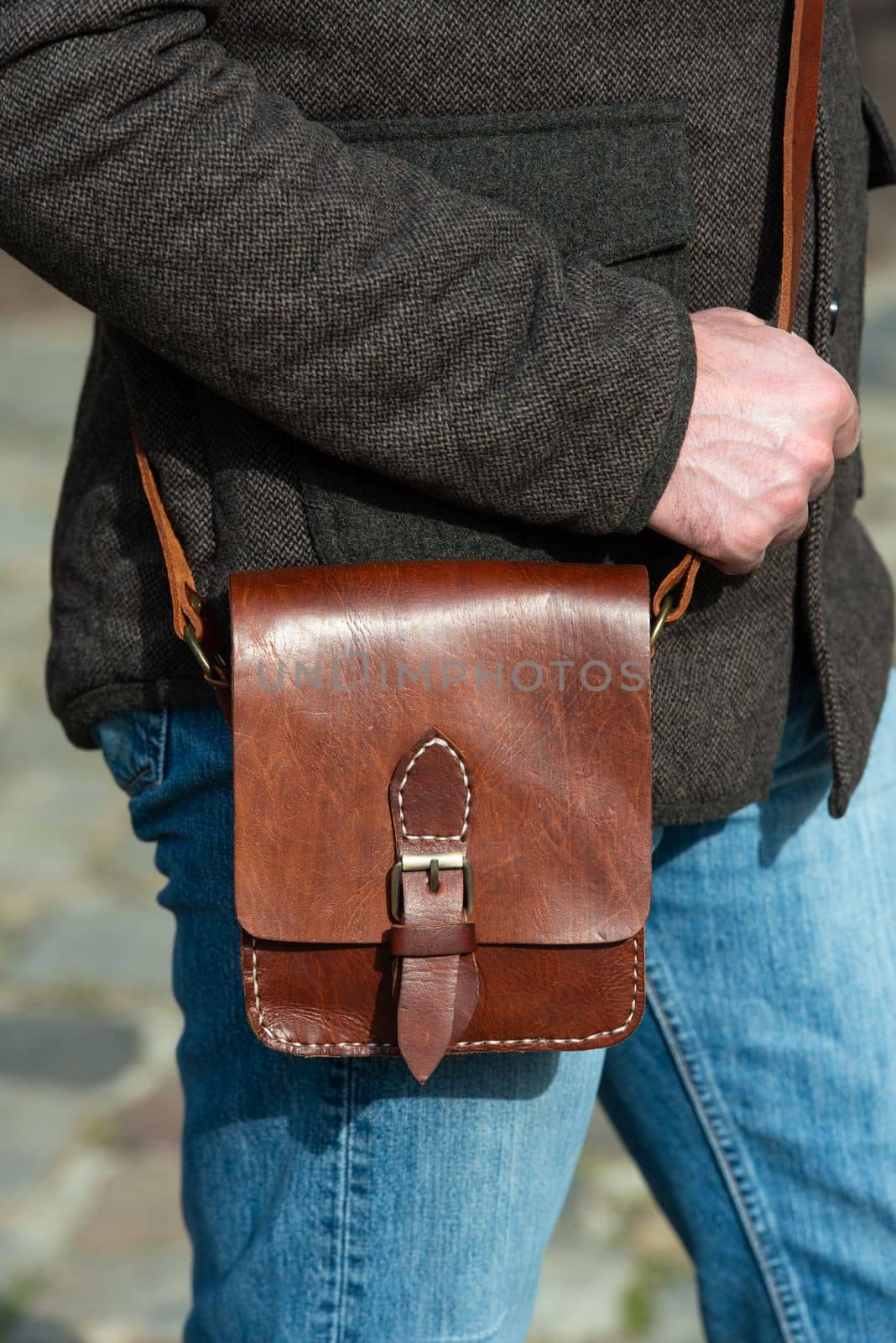 close-up photo of light brown messanger leather bag on mans shoulder by Ashtray25